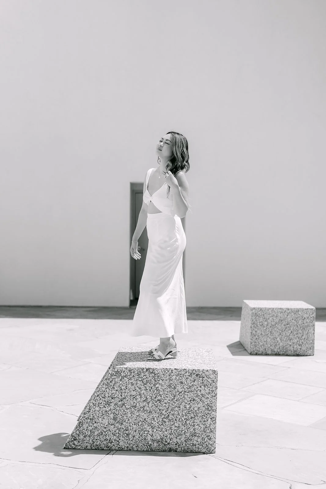 Black and white portrait of Stephanie on a granite block in the sculpture garden.