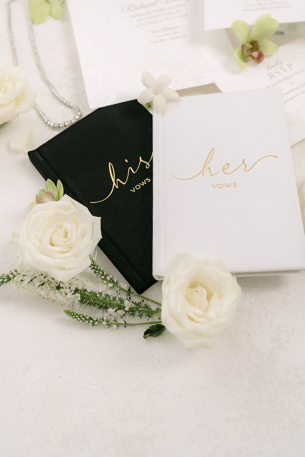 His and hers vow books styled with white roses and green orchids