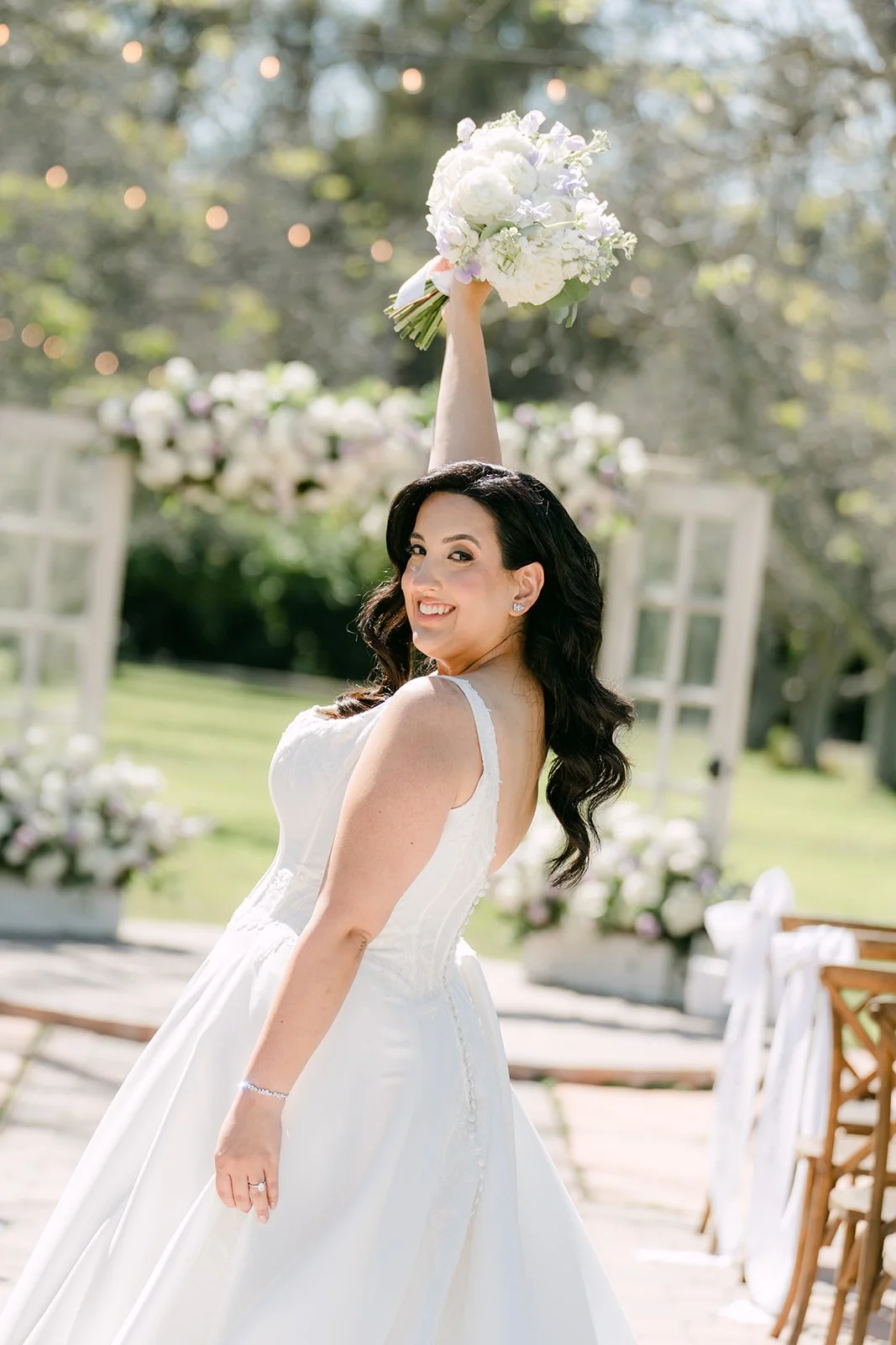 Bride raising her bouquet in front of the floral ceremony doors
