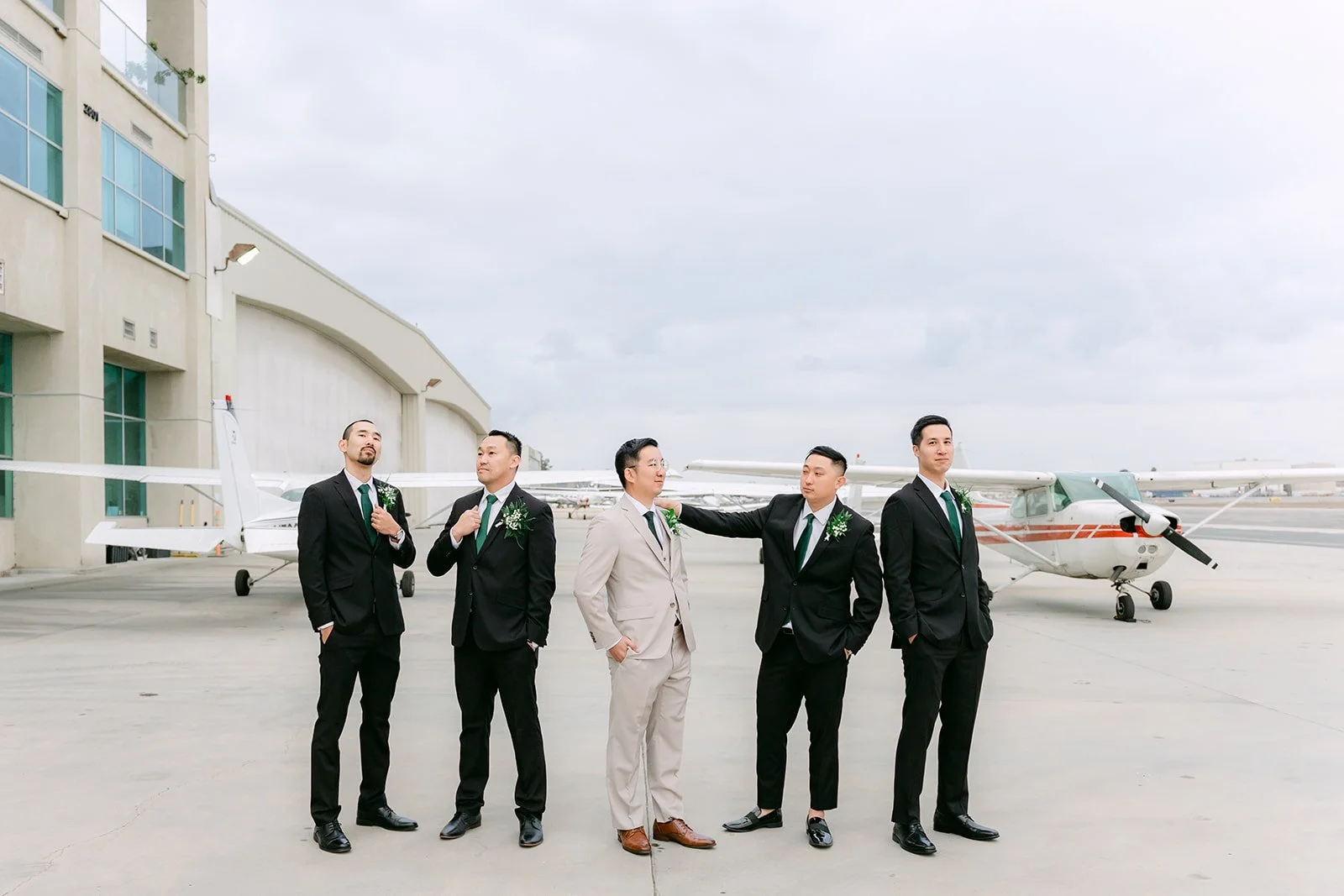 Groom and groomsmen posing outside the hangars