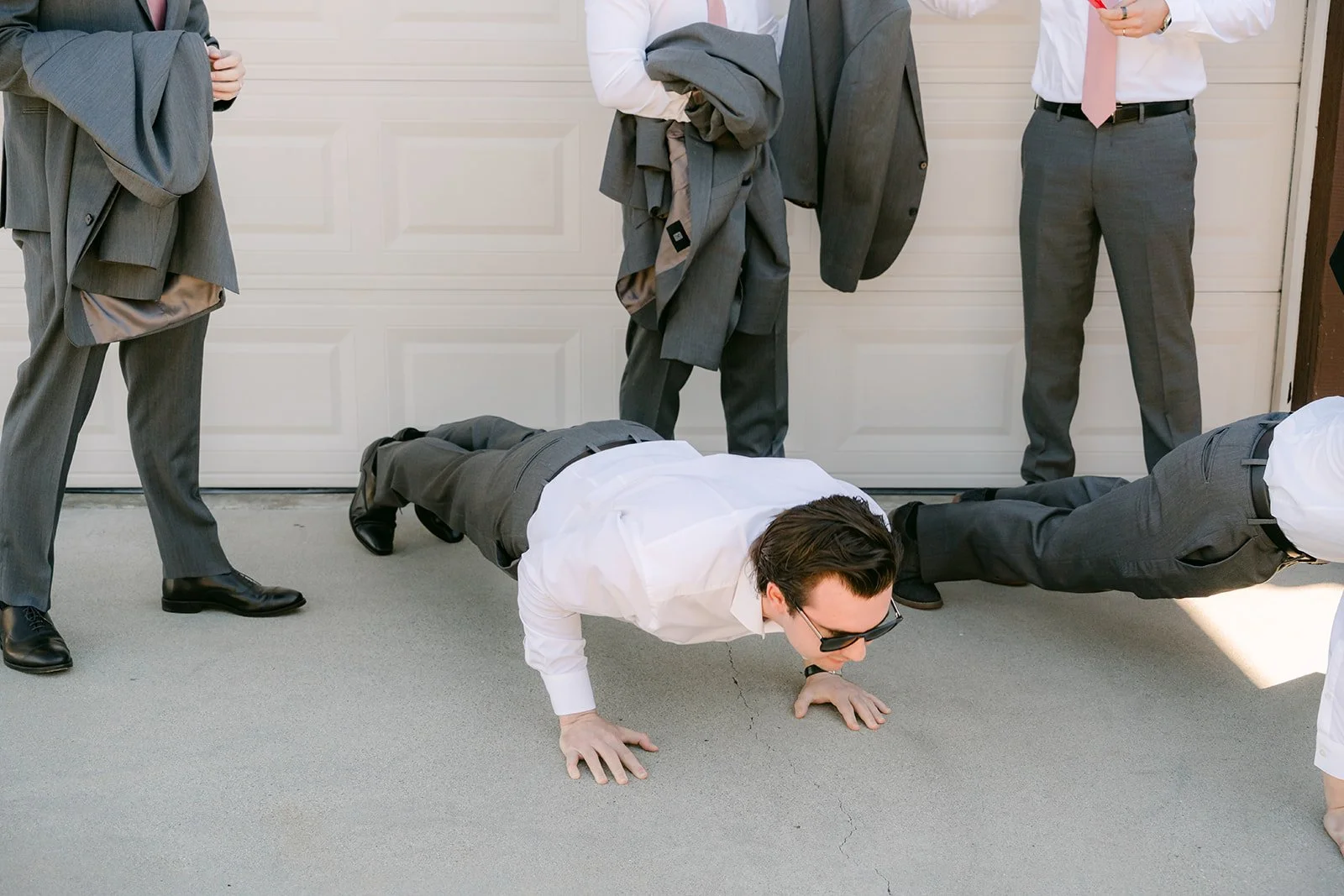 A groomsman doing push ups on the driveway.