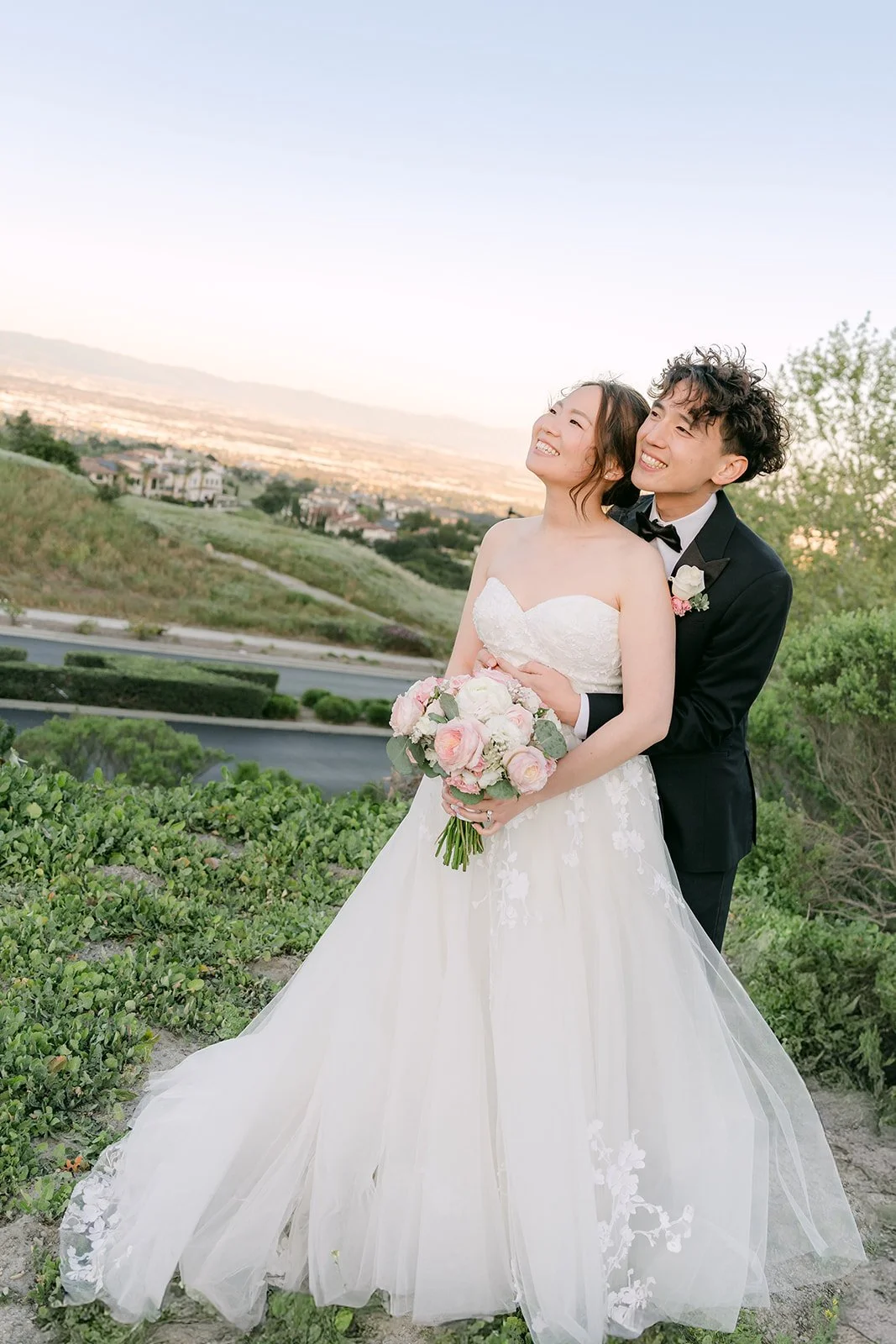 Couple laughing on the hillside with the valley behind them
