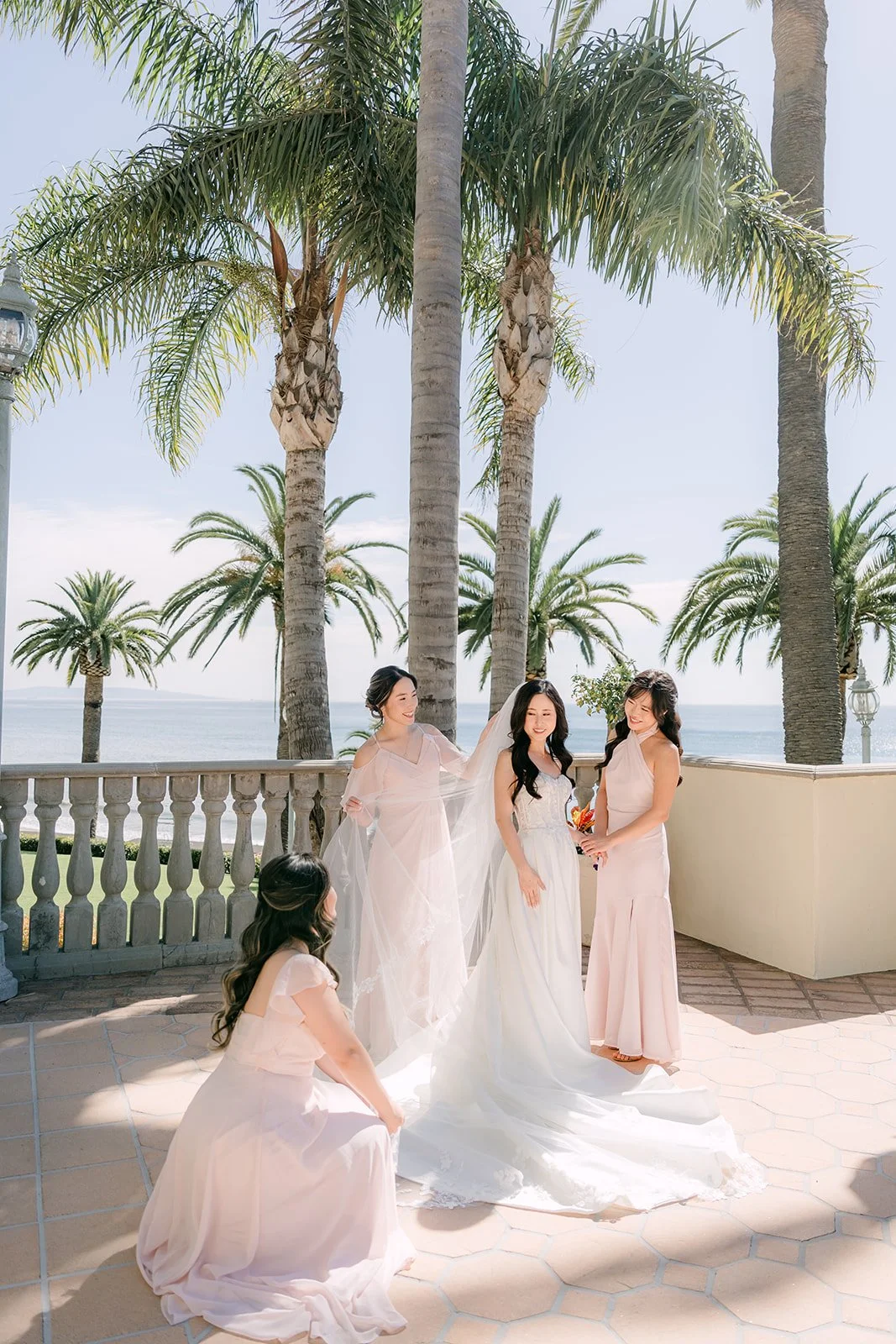 Bride with her bridesmaids in blush dresses under the palm trees