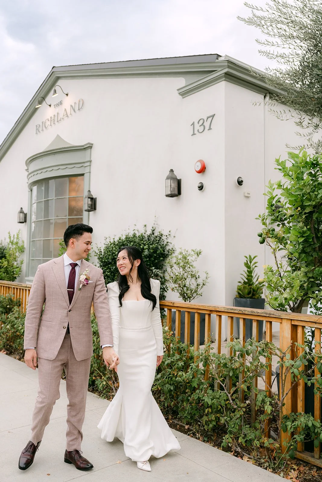 Denise and Michael walking outside The Richland past the fence and greenery.