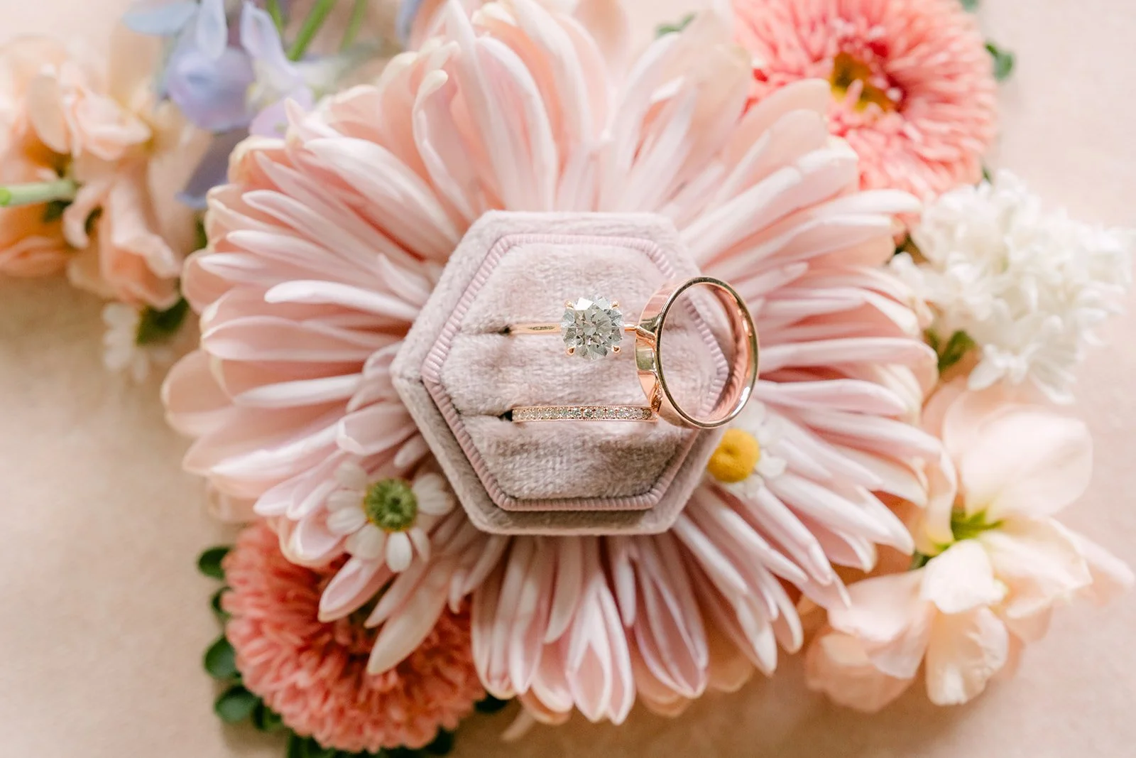 Engagement ring in a hexagon ring box nestled in a pink gerbera daisy