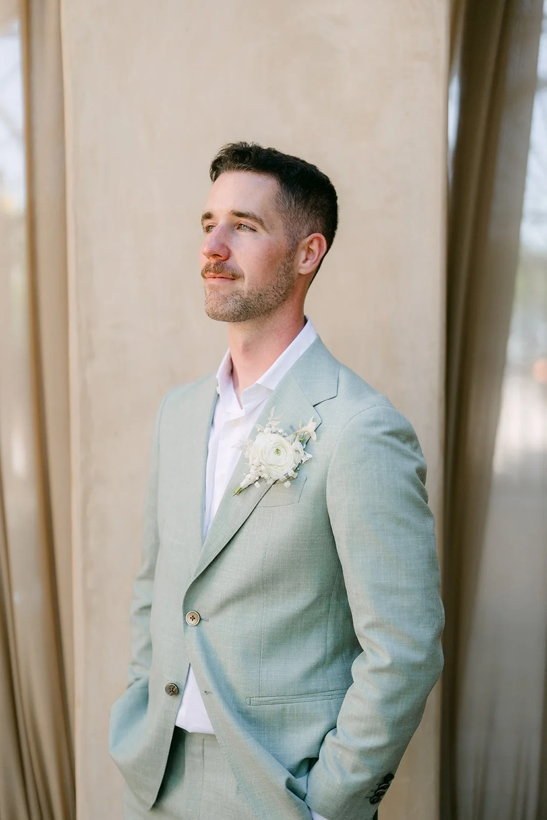 Anthony in his sage suit beside the drapery, photographed by One and Only Production