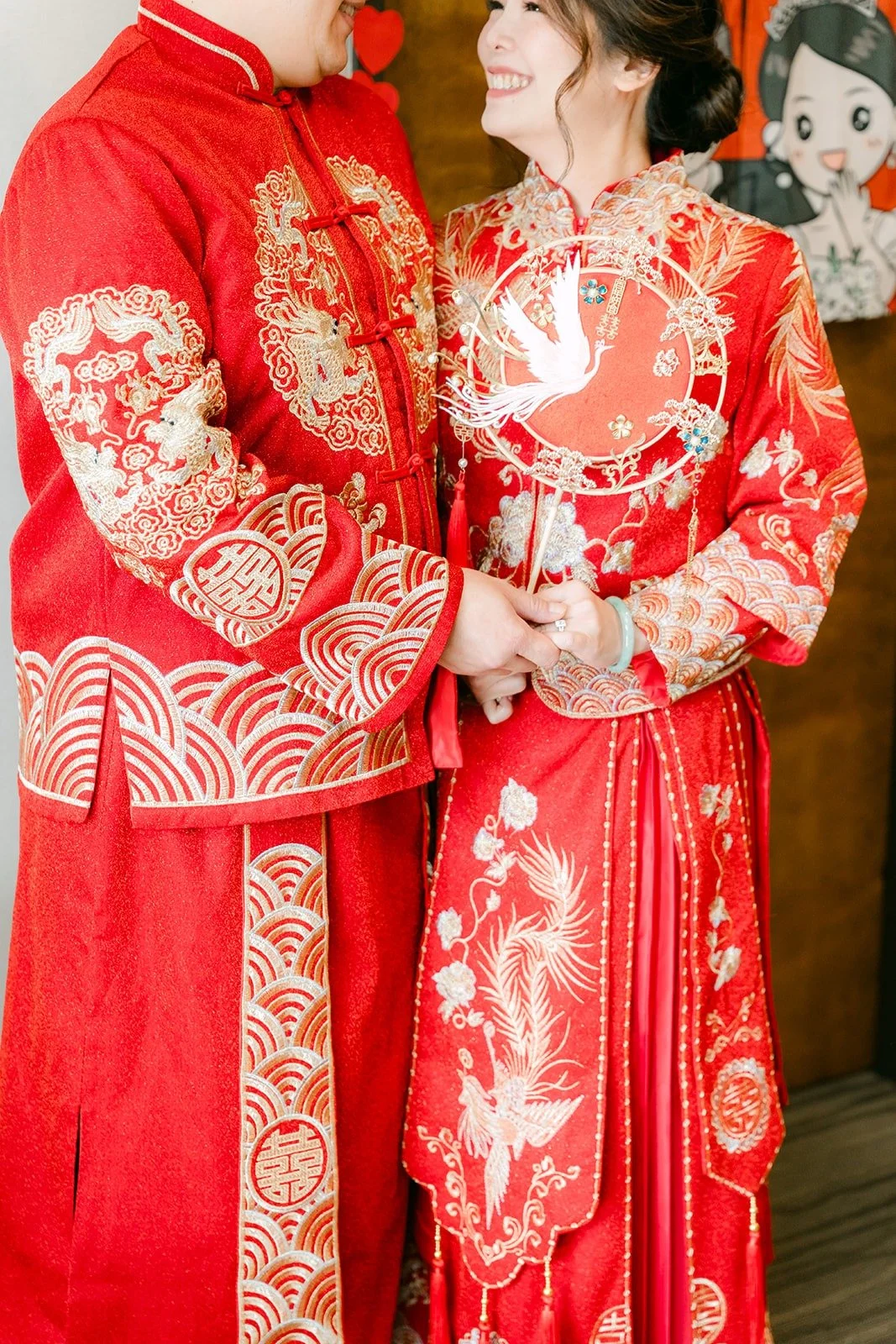 Sochi and Jay in red and gold embroidered wedding attire side by side, photographed by One and Only Production