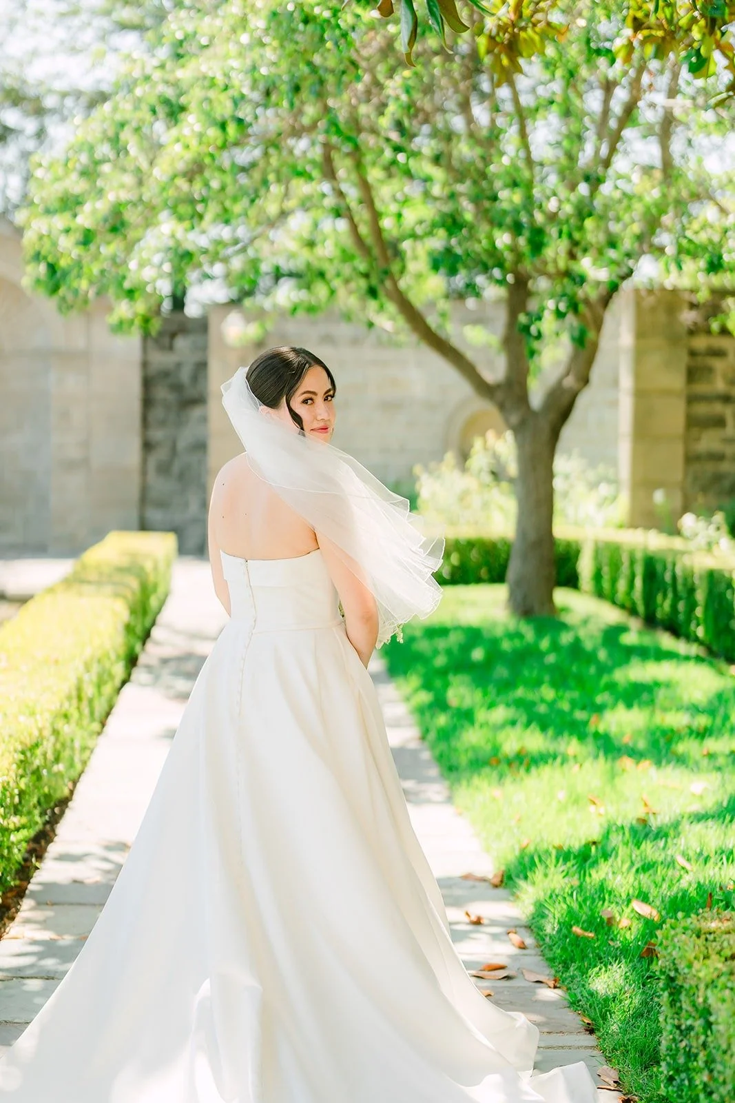 Brianna walking through the formal gardens with her veil trailing