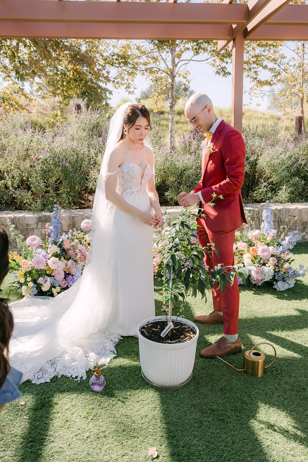 Christie and Christian standing together at the front of the ceremony beside a potted plant.