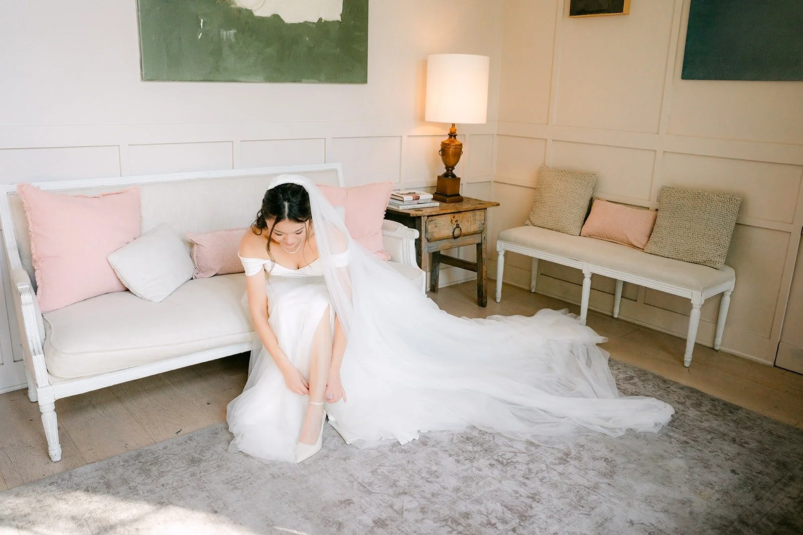 Jadee in her wedding gown on a white sofa in the bridal suite at The Harper
