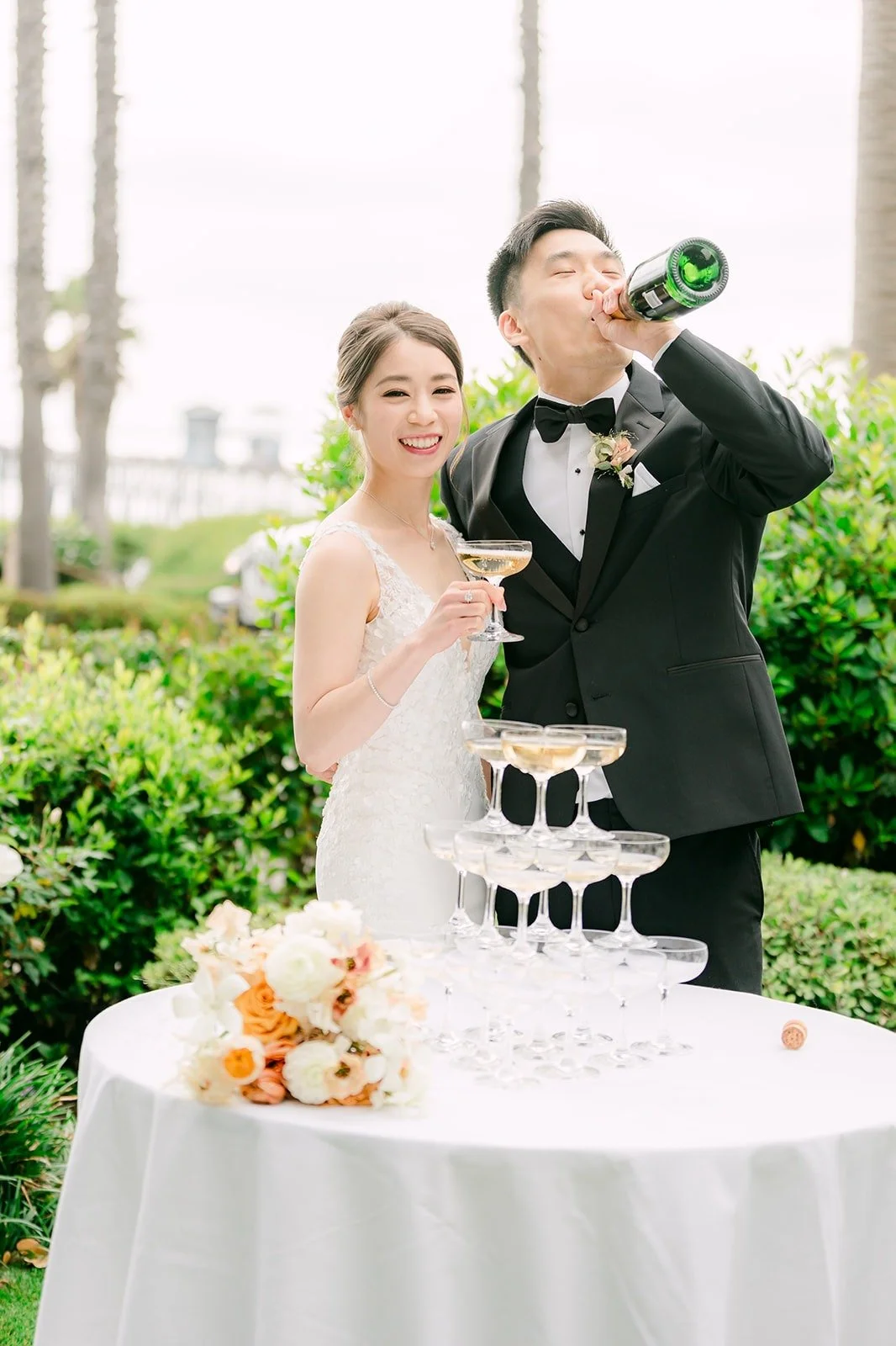 Eli pouring from the bottle as Angela watches the glasses fill
