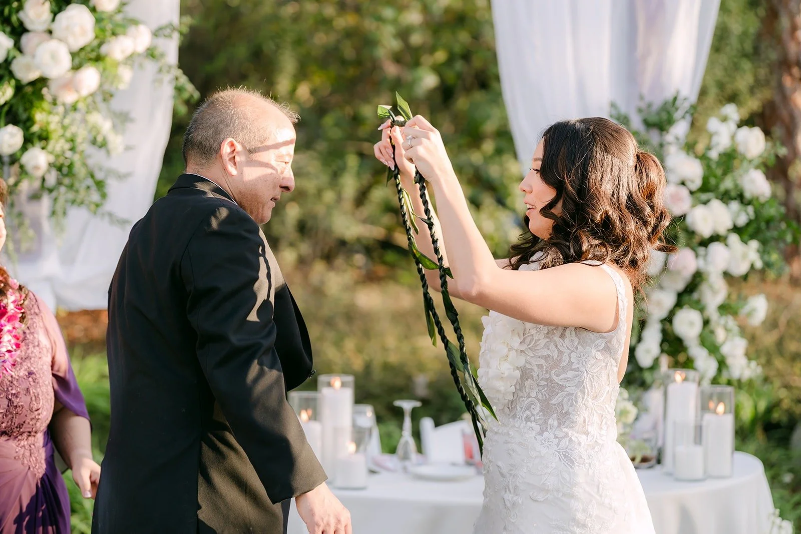 A family member placing a white flower lei on Kelli