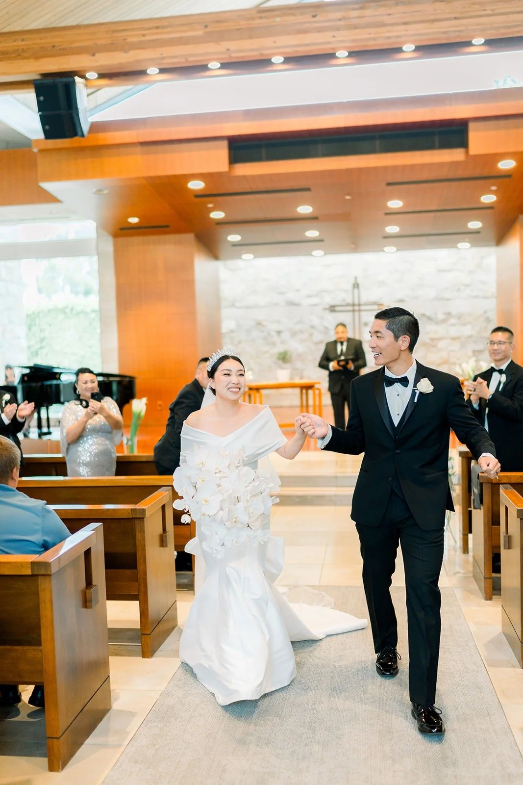 Steven and Jacinda celebrate as they walk back up the aisle, photographed by One and Only Production