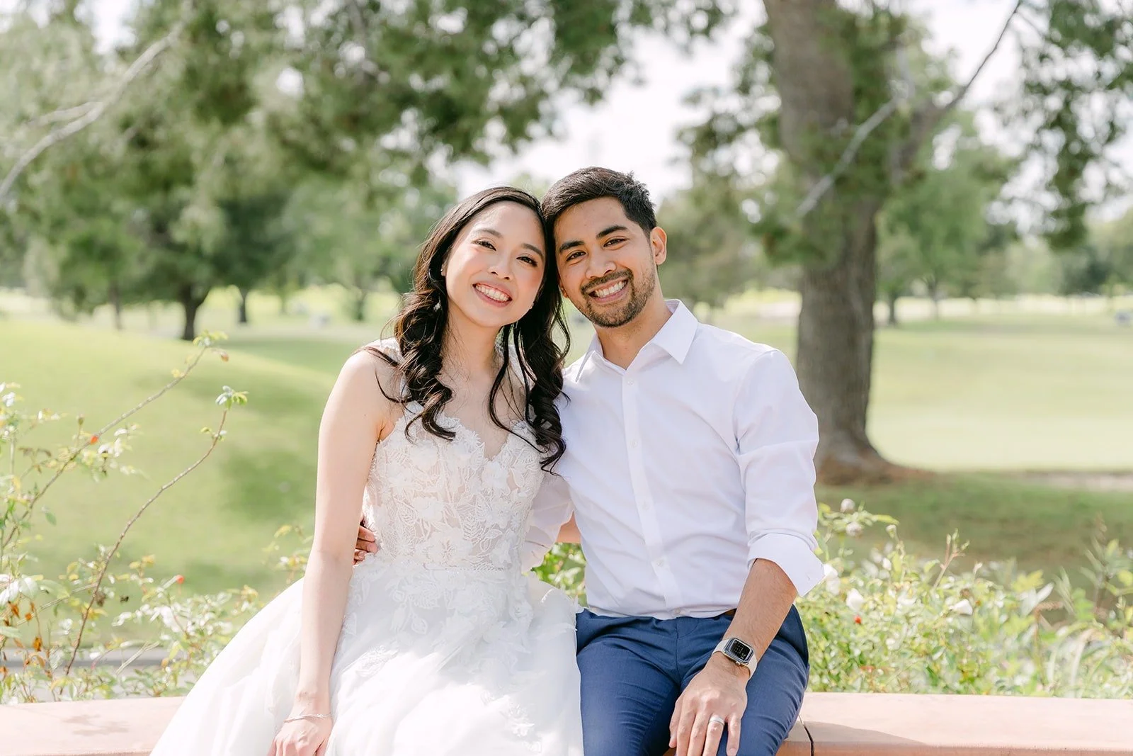 Natalie and Mark laughing together on a stone wall overlooking the golf course