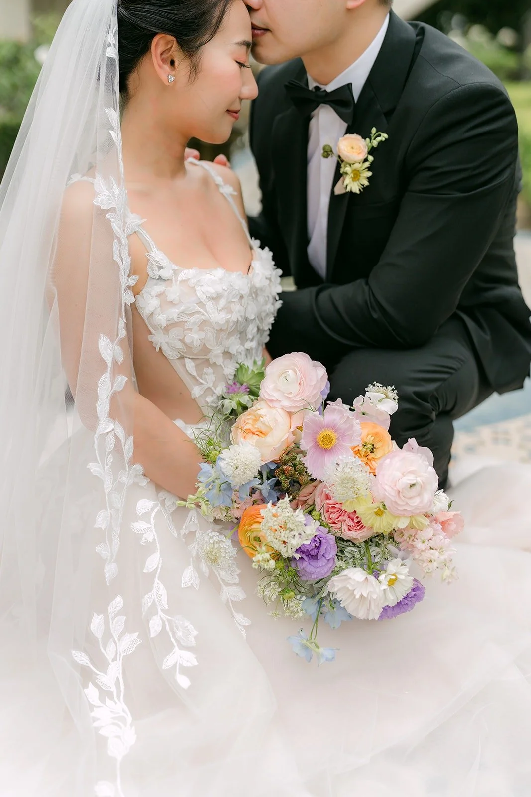 Mario kissing Kylie's forehead as she holds her bouquet