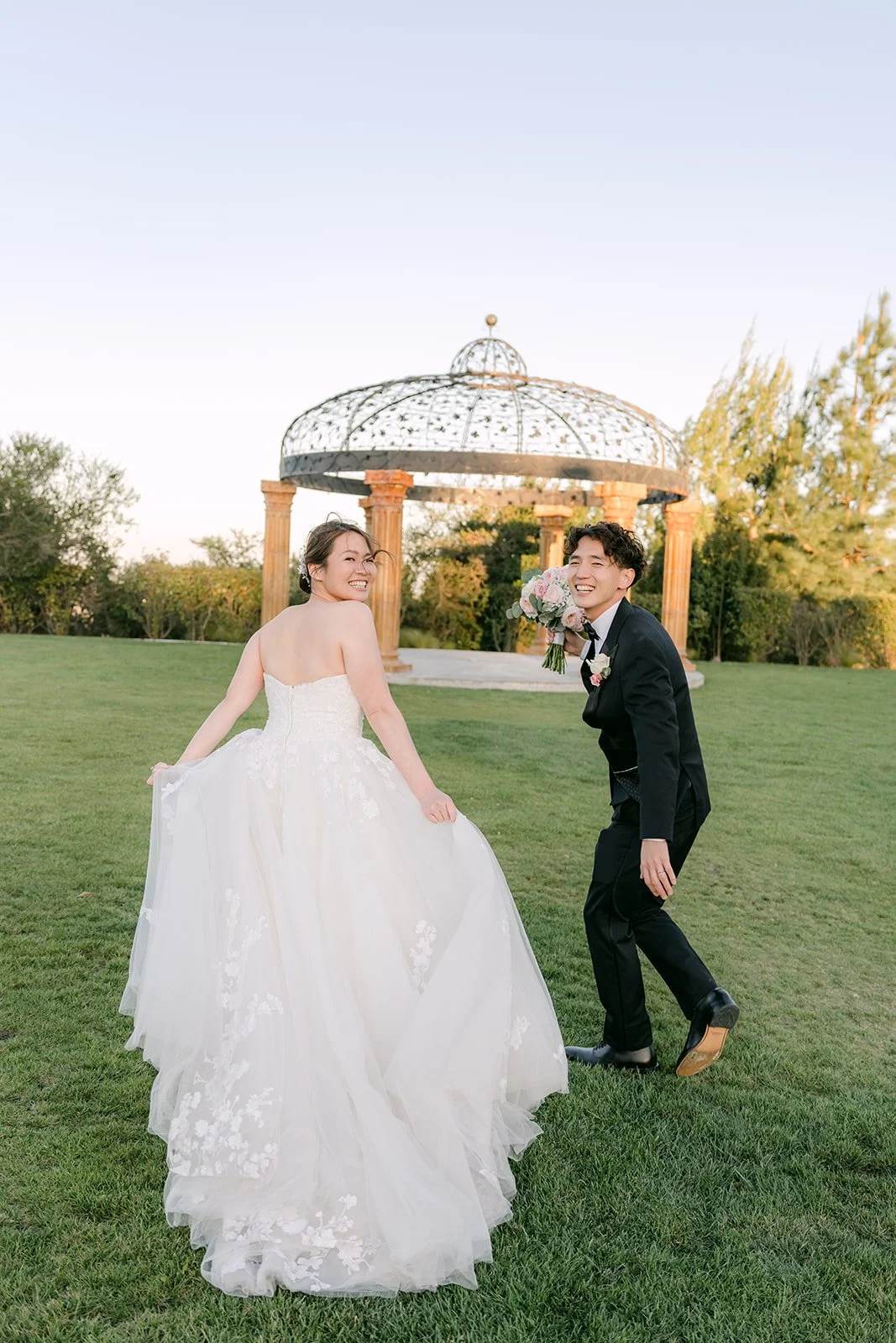 Bride twirling her gown as Tony dances toward her by the gazebo