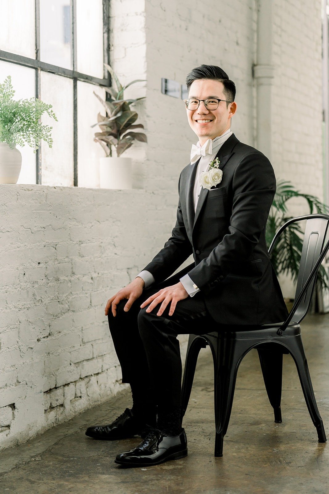 Alex seated in his tuxedo by the windows