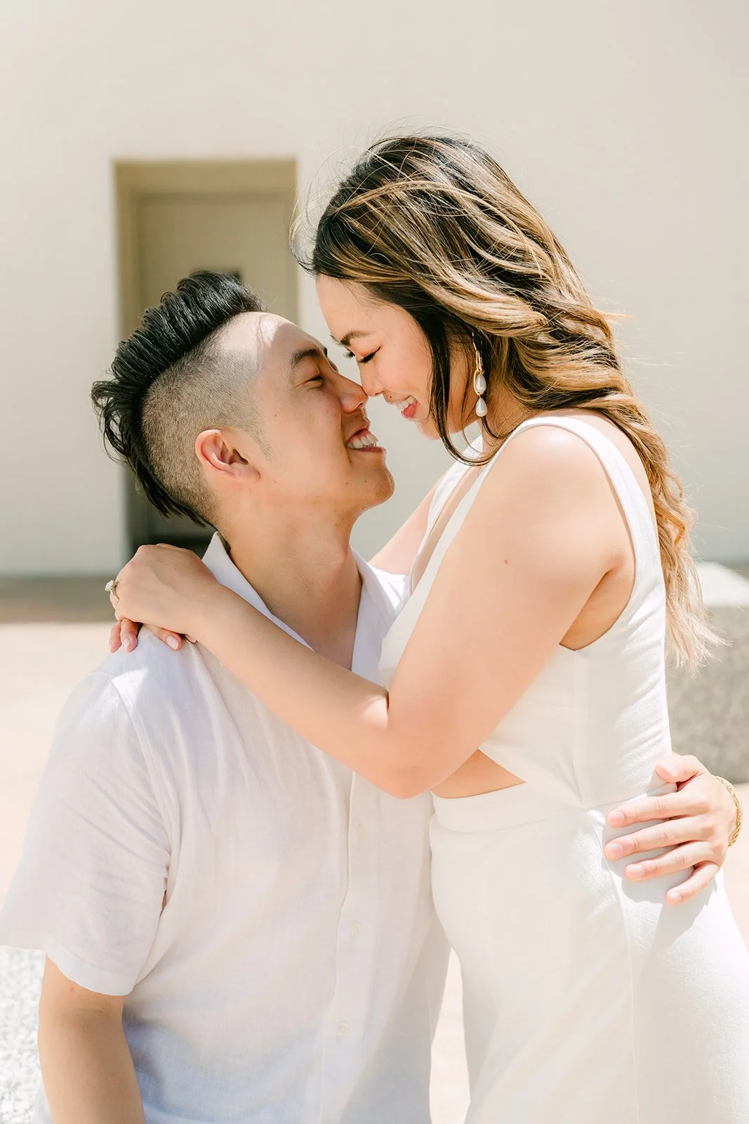 Stephanie and Alan nose to nose by the white wall.