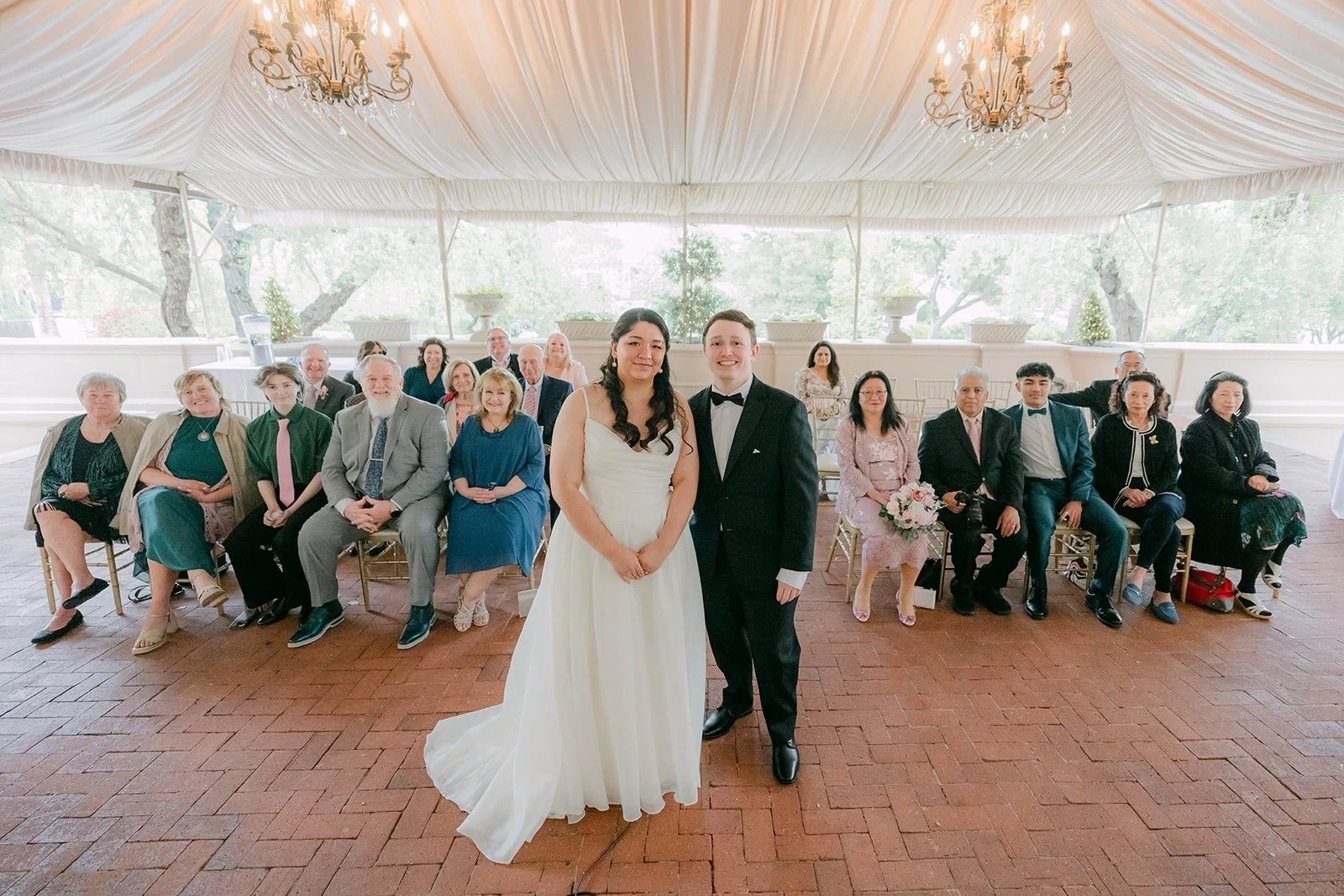 Saira and Matthew facing their guests under the chandeliers