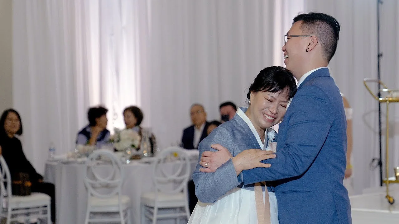 Video still of a parent dance in front of the white drapery
