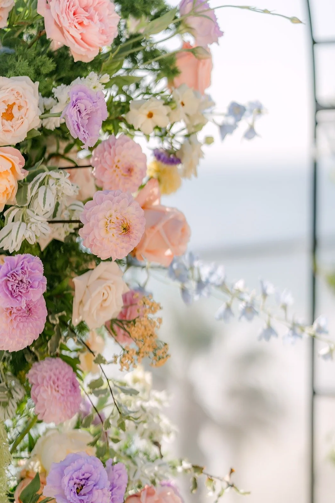 Close view of the peach, lavender and pink blooms on the ceremony arch