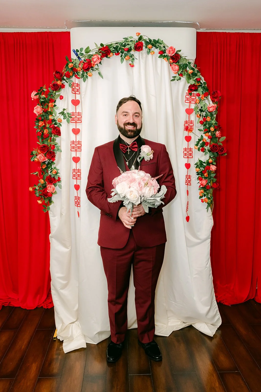 Ryan holding the bouquet in his burgundy suit.