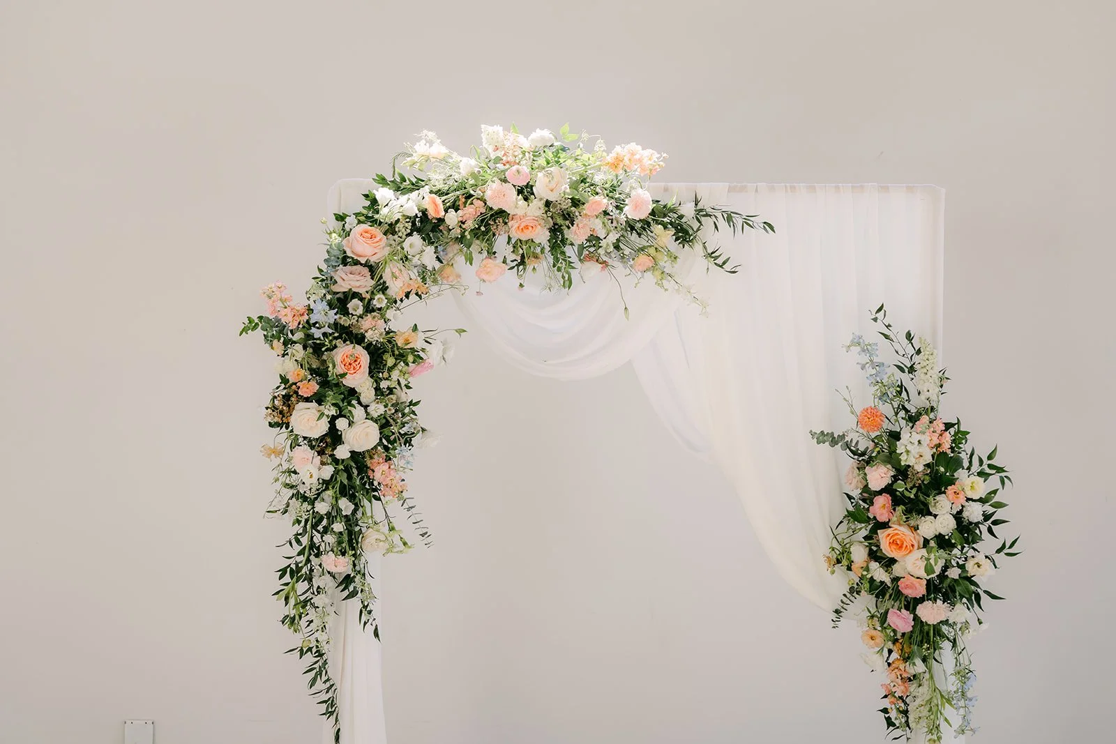 White floral arch with peach and pink roses