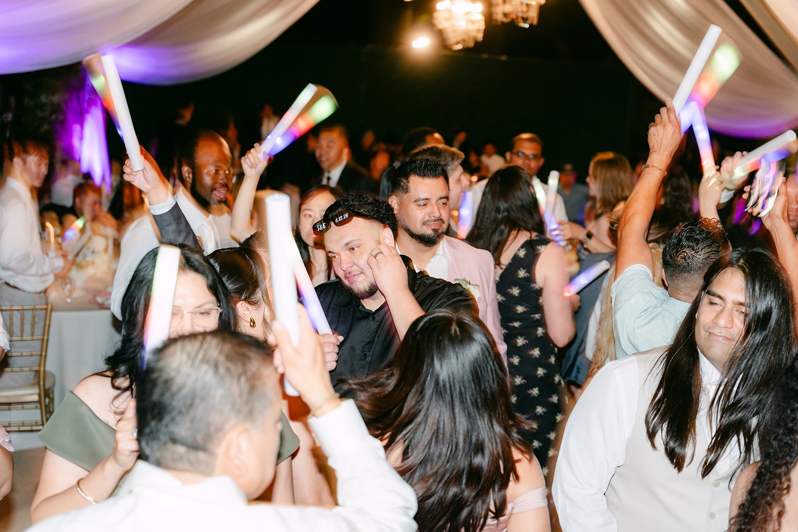 Guests waving glow sticks on the packed dance floor.