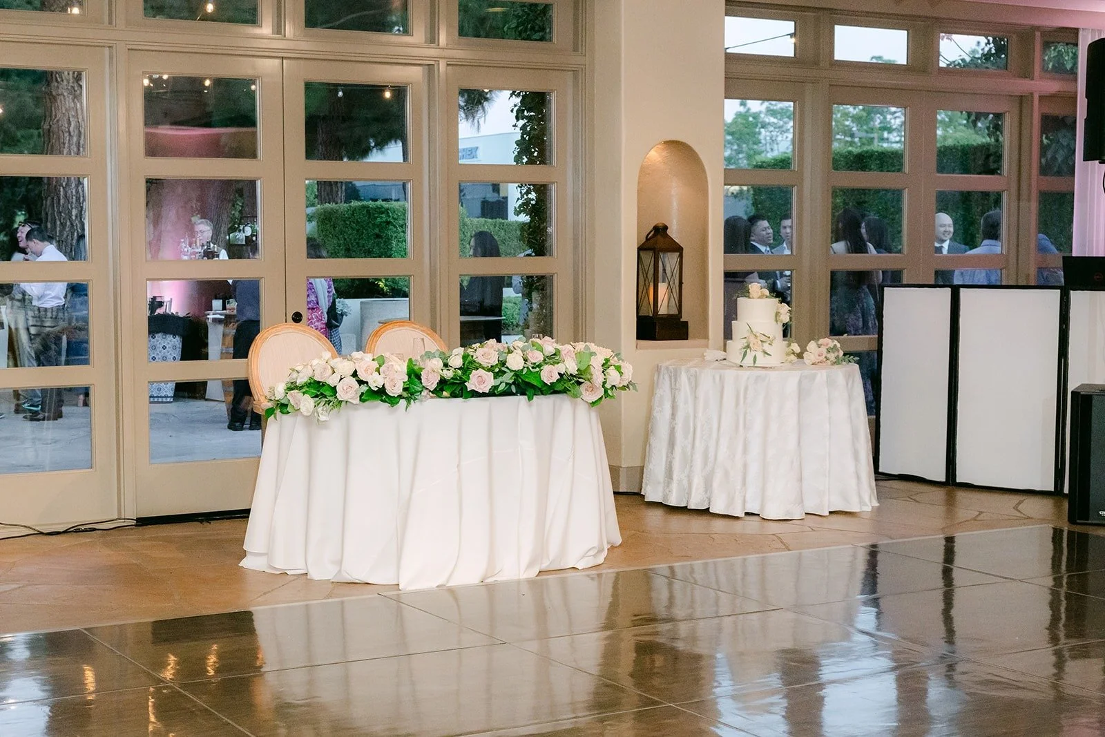 Sweetheart table with white flowers in front of the ballroom windows