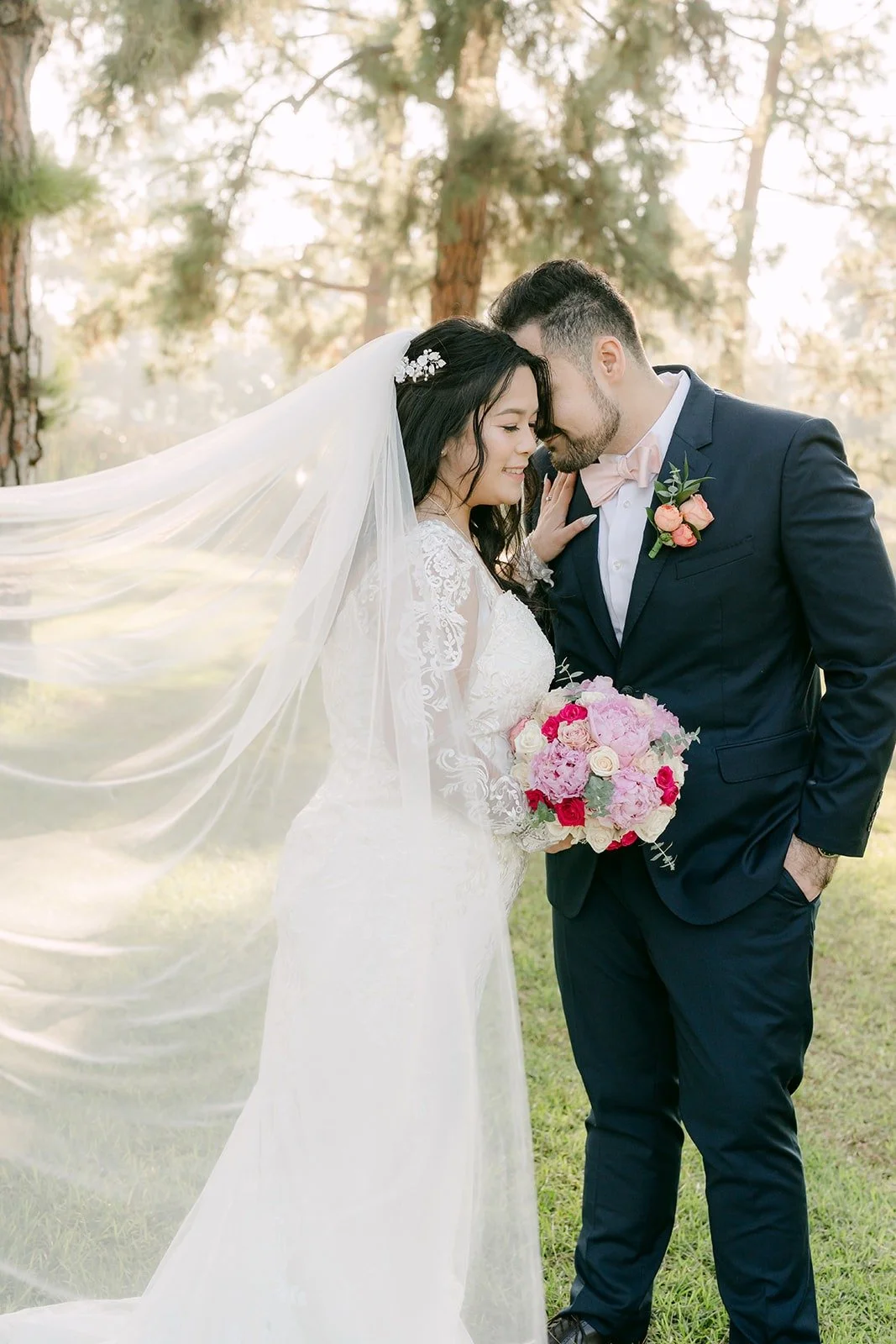 Amy and James wrapped in her veil in the golden haze