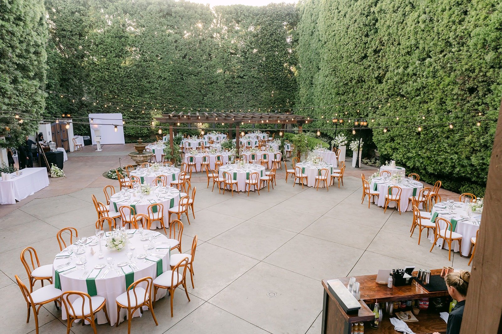 Round reception tables set with white linens in the courtyard