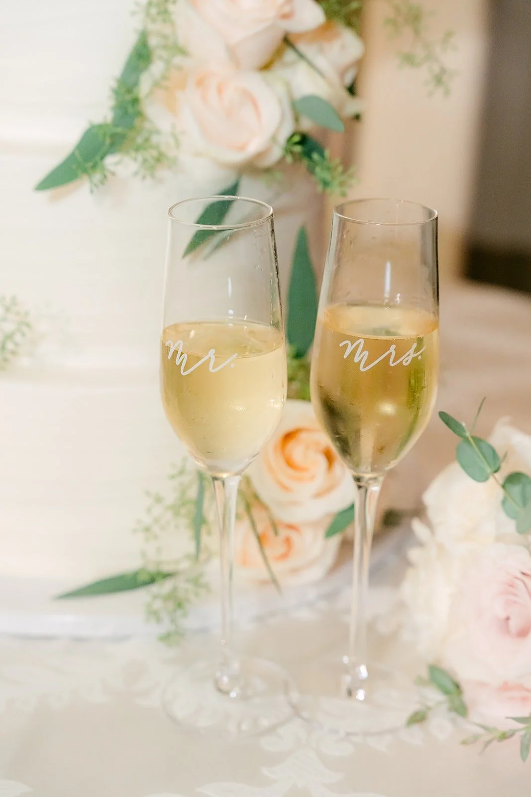 Champagne flutes beside white roses at the sweetheart table