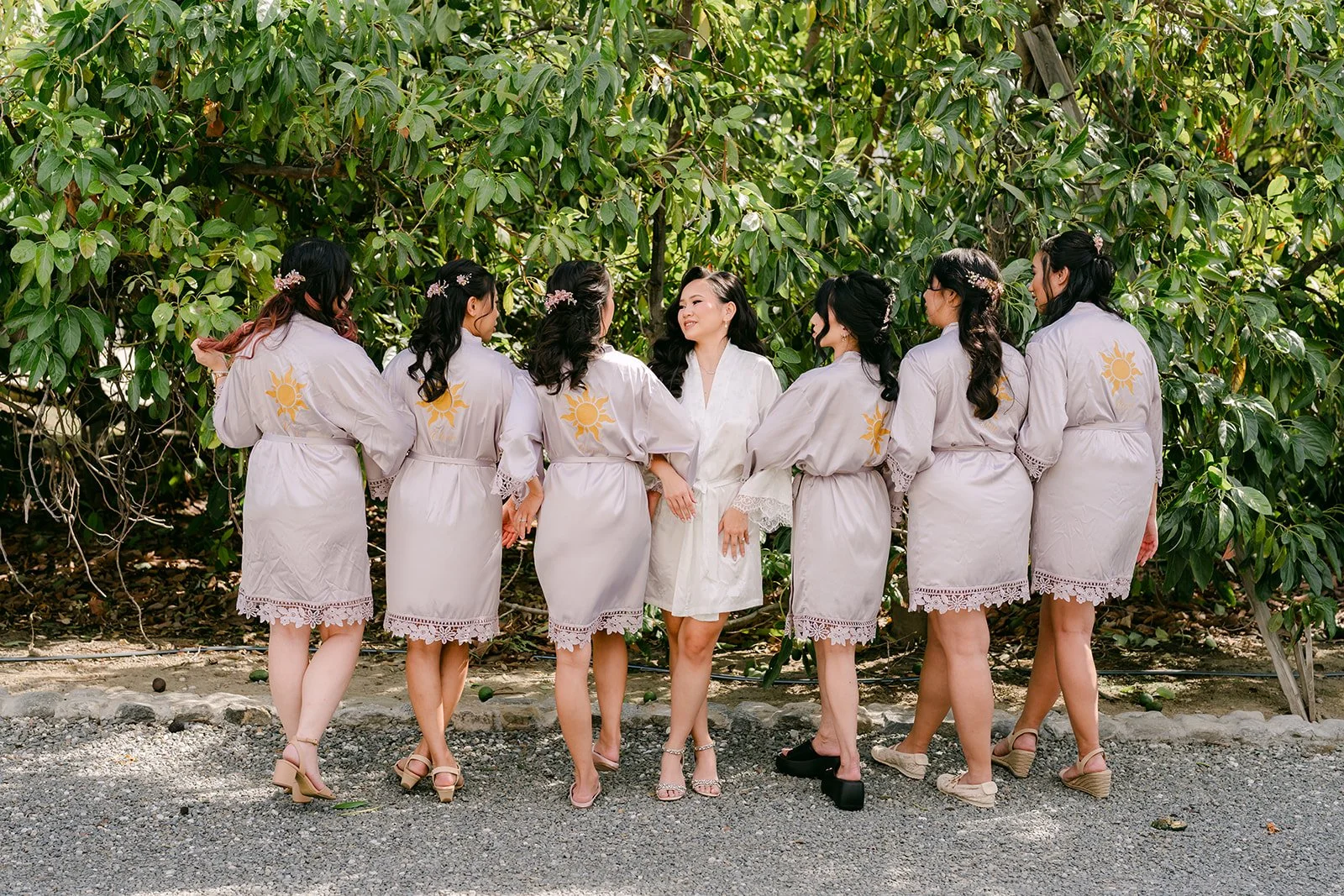 Bridesmaids in robes with sun emblems on the back.
