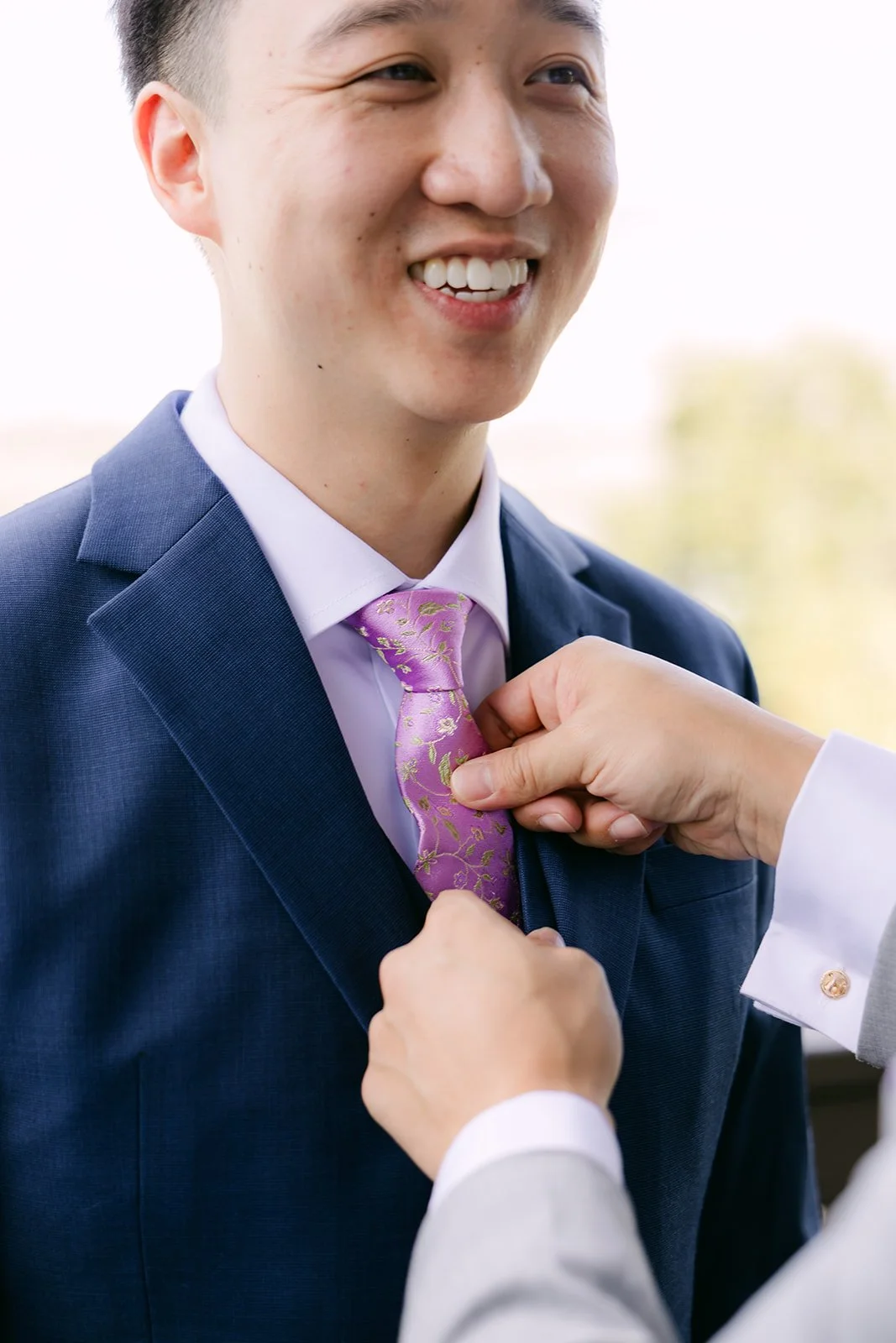Elijah laughing as his tie is adjusted.