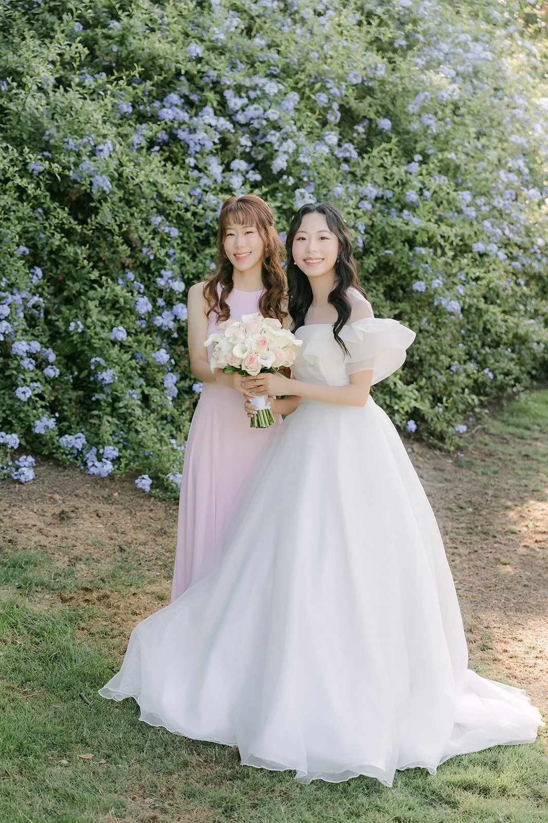 Jeannie and Stephanie standing together in front of the blooming hedge