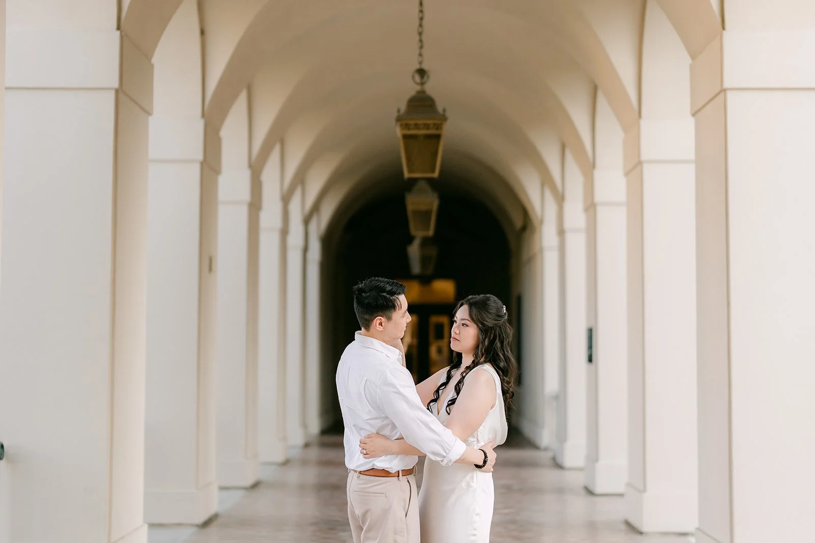 Emily and James framed at the end of a row of arches.