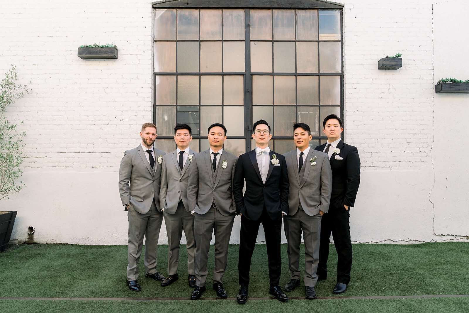 Alex and his groomsmen lined up on the turf by the steel framed windows