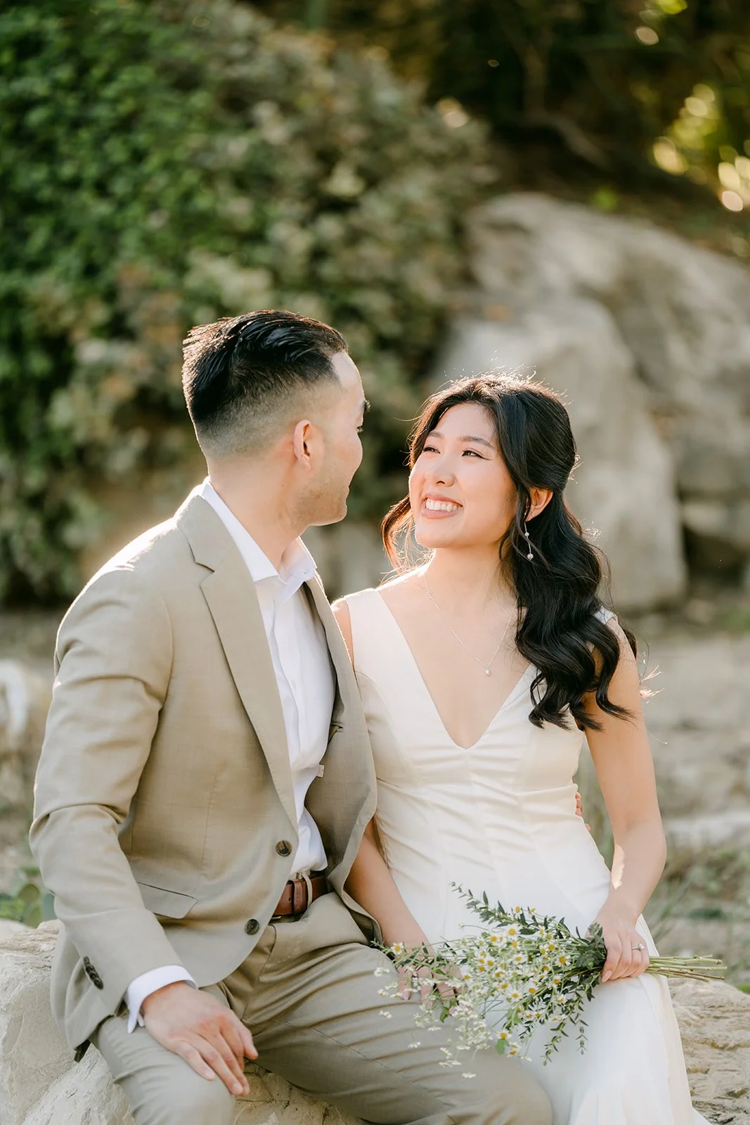 Kim and Vincent seated together on a boulder in the garden.