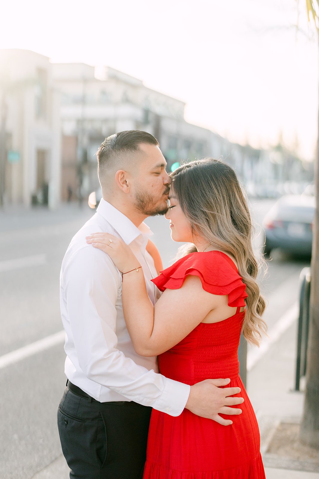 Ankush kisses Linh's forehead on the sidewalk.