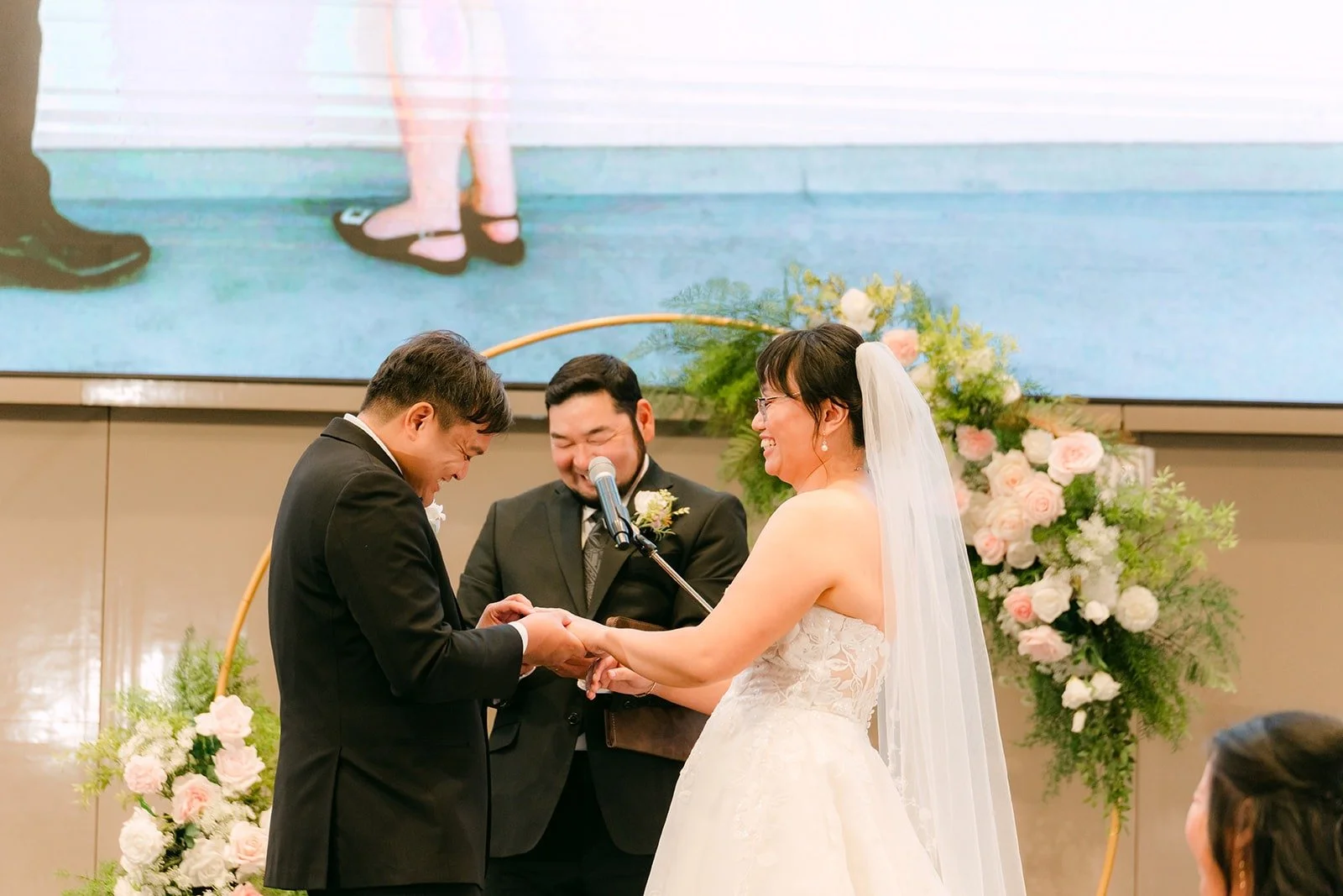 Stella and James exchanging rings under the floral arch