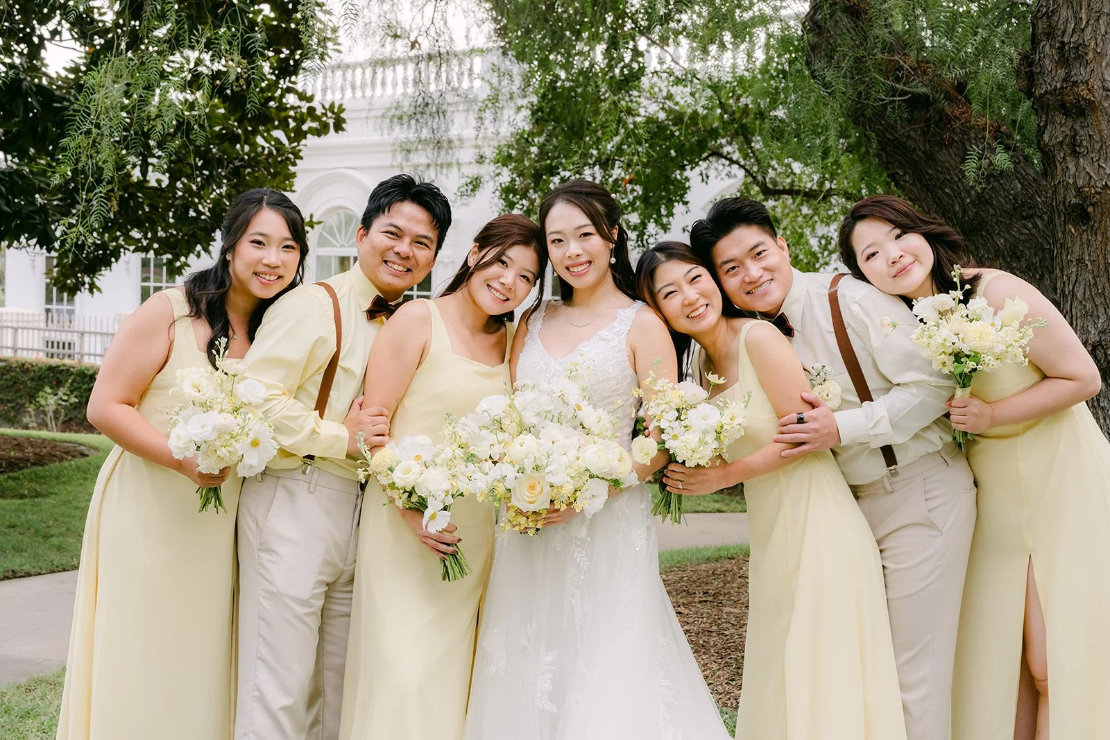 Jenny and her bridesmaids huddled together with white and butter yellow bouquets.