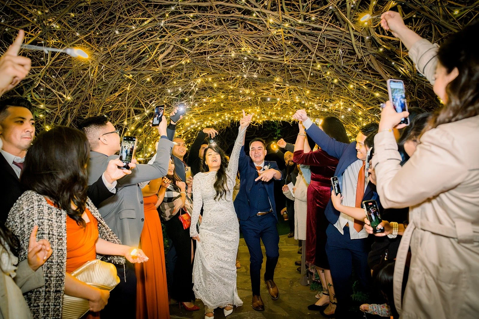 Guests lining the twinkling tree tunnel for the grand exit