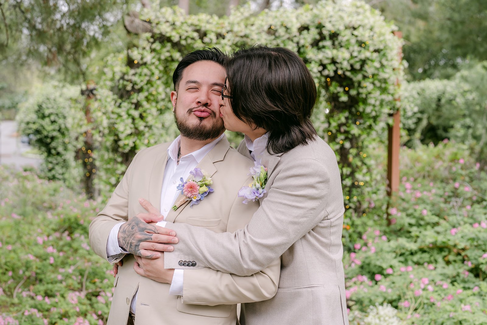 Groomsman hugging Mike and planting a kiss on his cheek