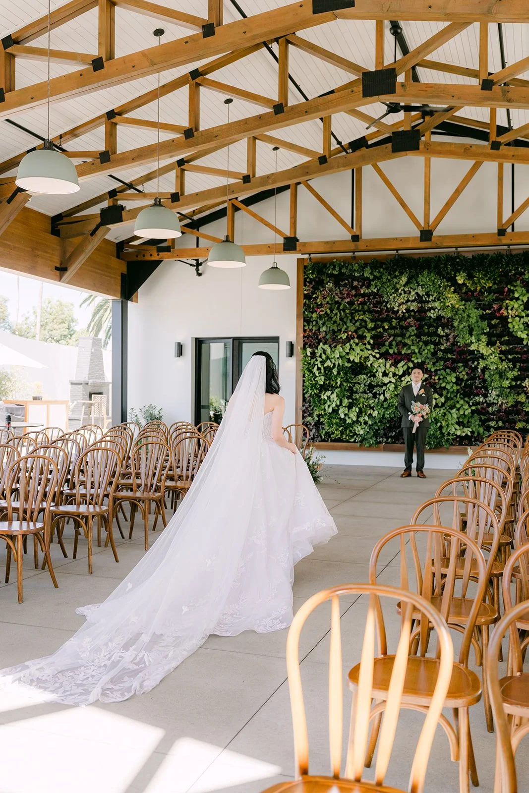 Vivian walking under the wood trusses of the Colony House Pavilion with her long train