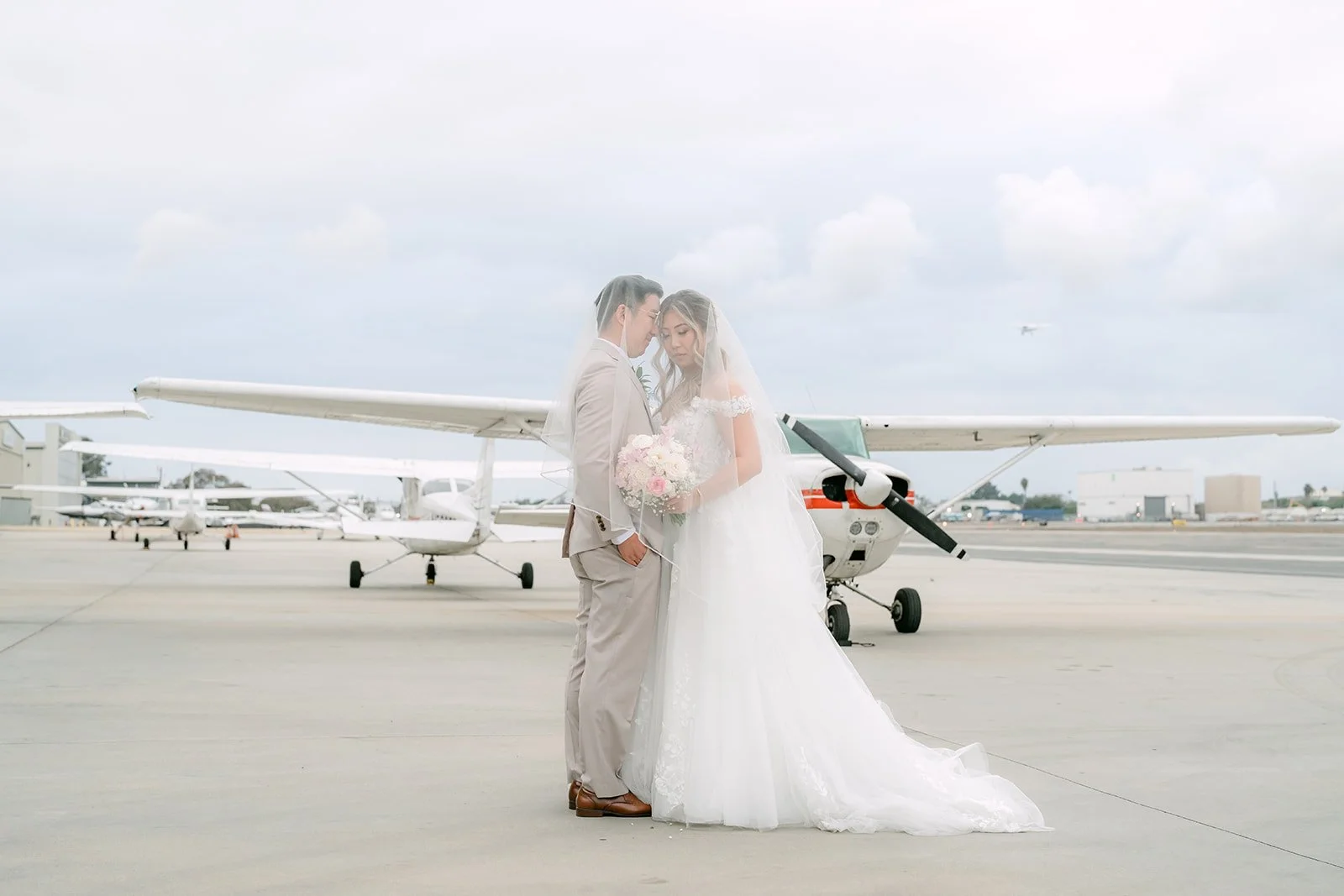 Couple sharing a kiss on the tarmac with Cessnas behind them