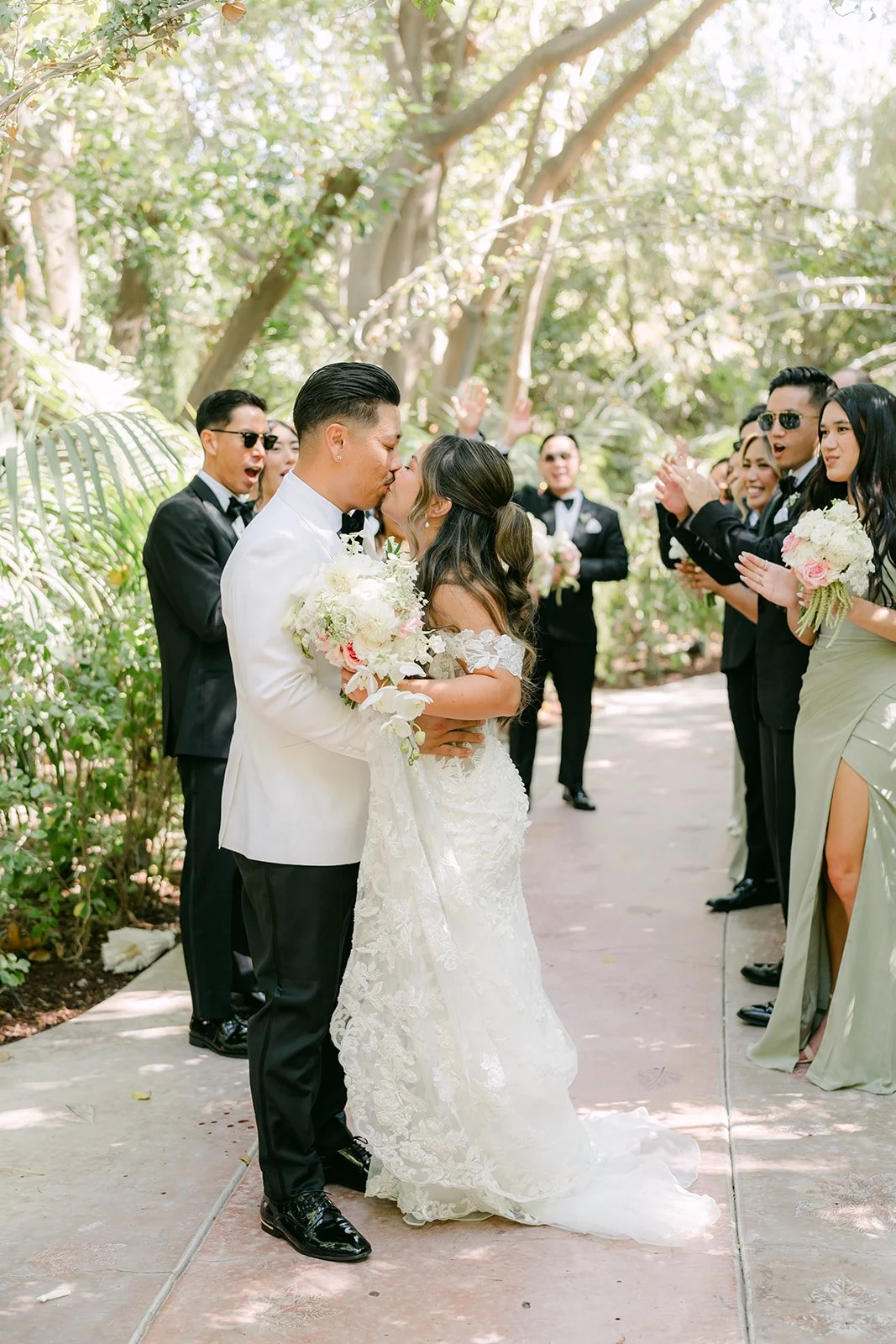 Caryl kissing Nicole's cheek as their wedding party cheers.