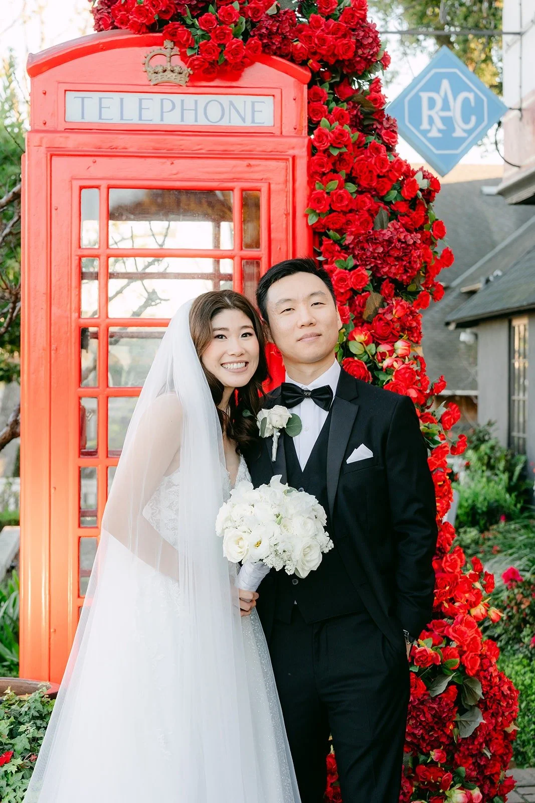 Valerie and Jason in front of the red phone booth covered in roses