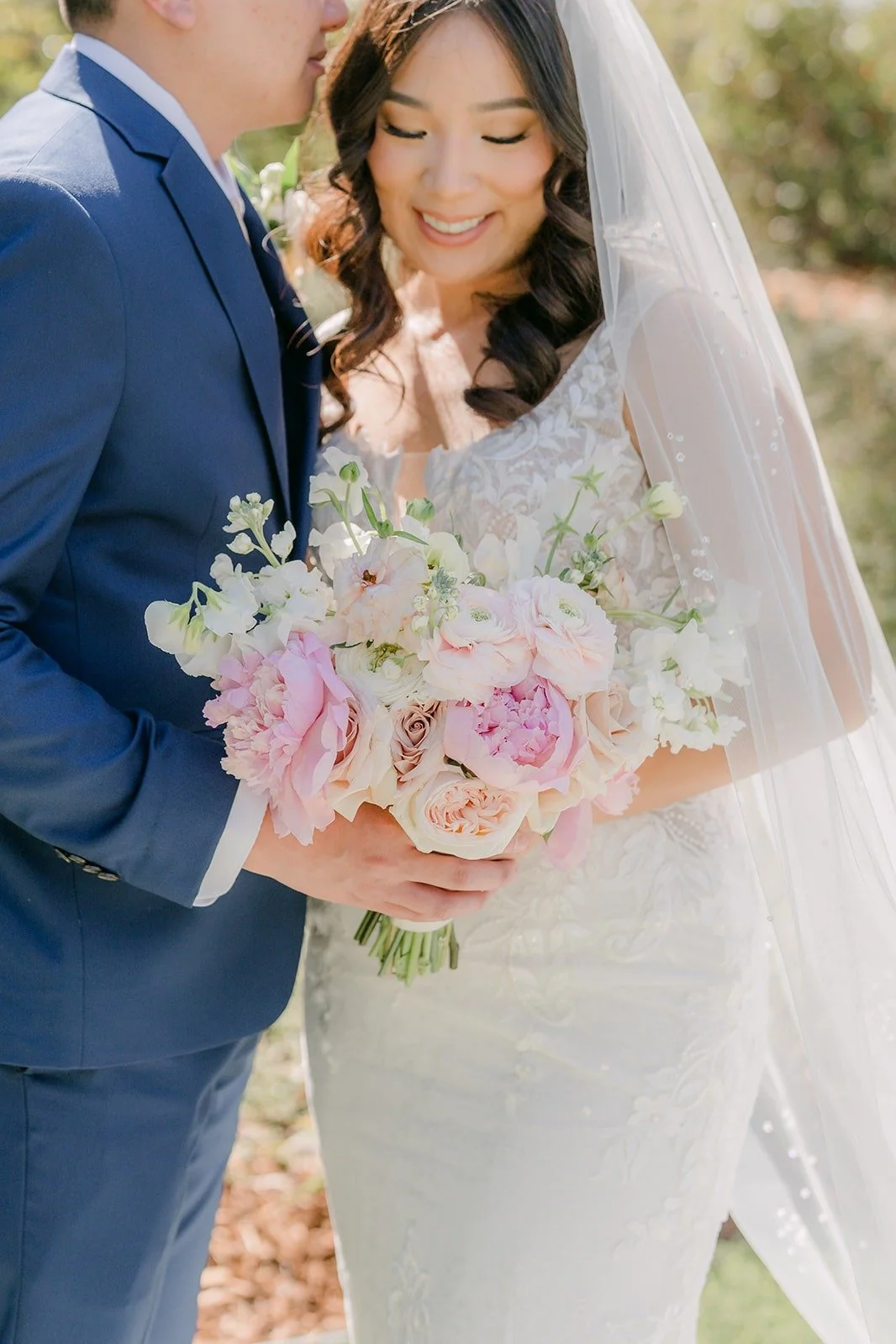 Kelli holding her bouquet of ivory and blush roses close to Alex