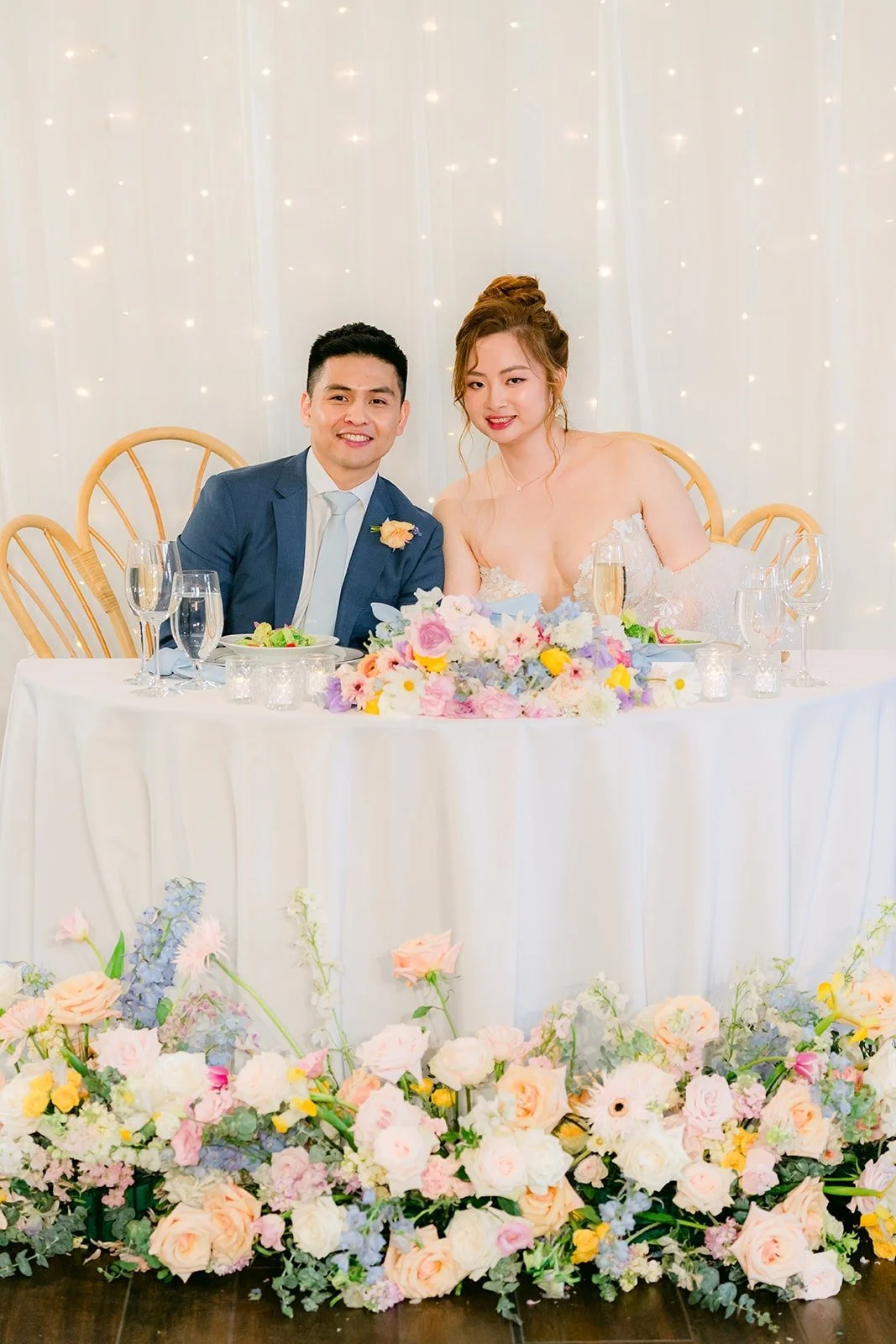 Joanna and Jerrick at their sweetheart table lined with pastel florals