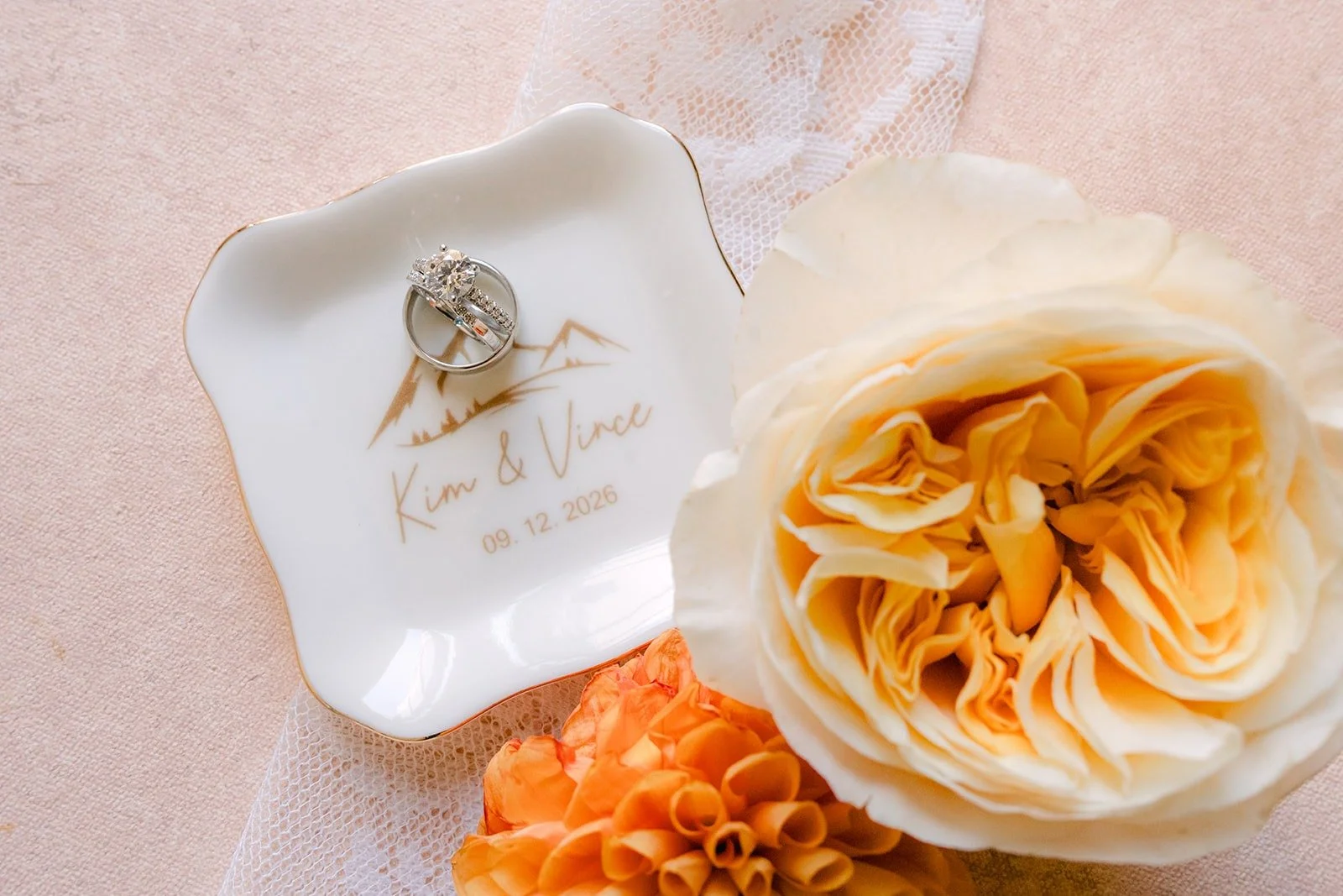 Kim's engagement ring in a custom ring dish beside peach garden roses